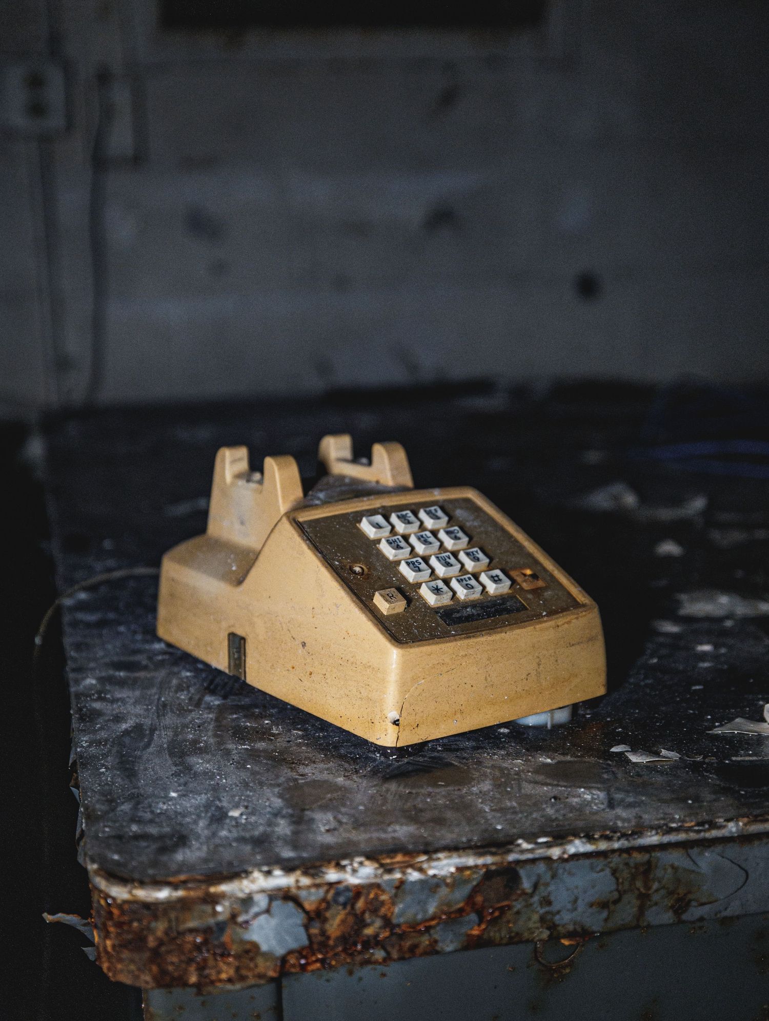 Old beige numeric keypad lying on a weathered dark surface.