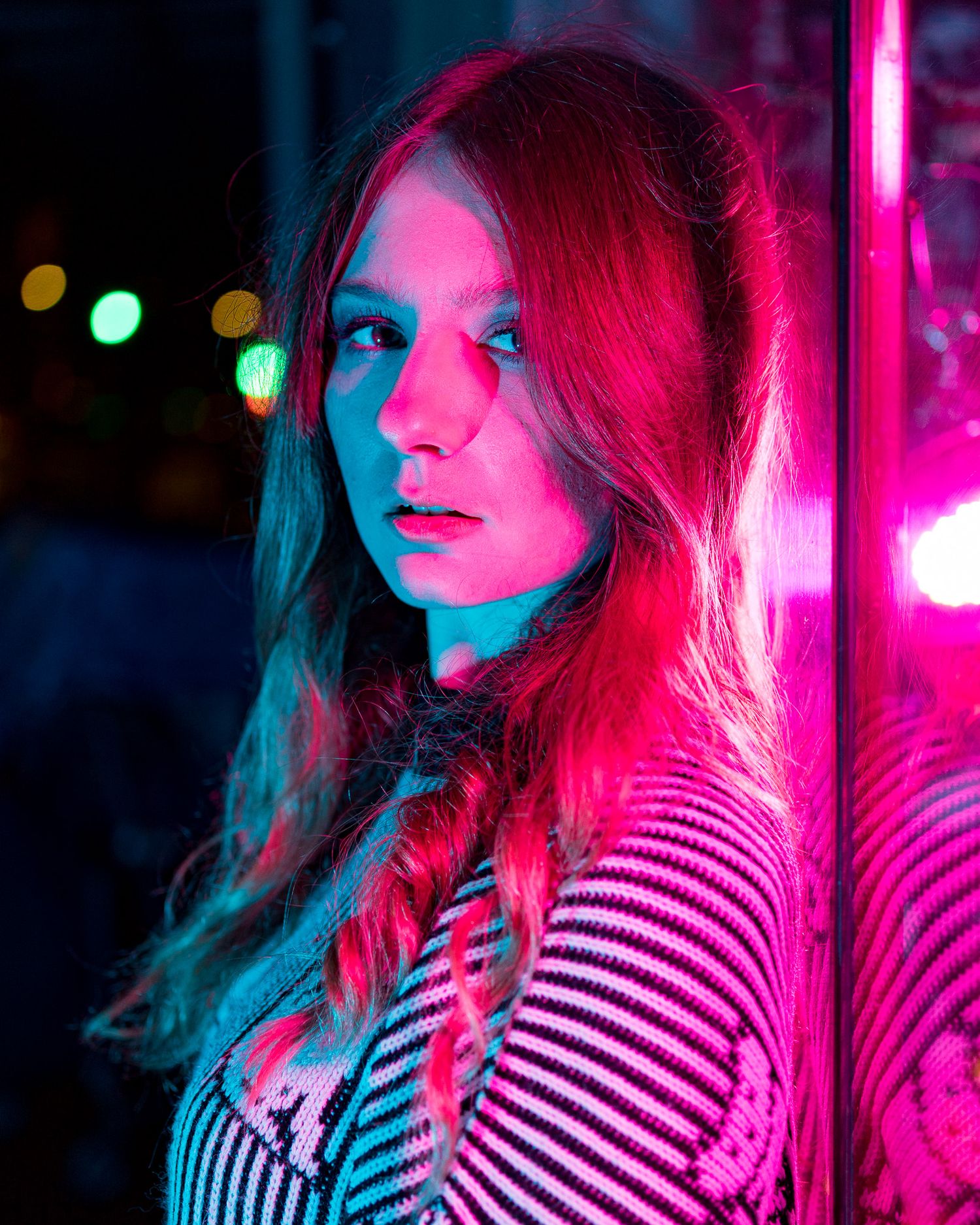 Neon-lit portraits in striped clothing creating a vibrant pink and blue color palette.