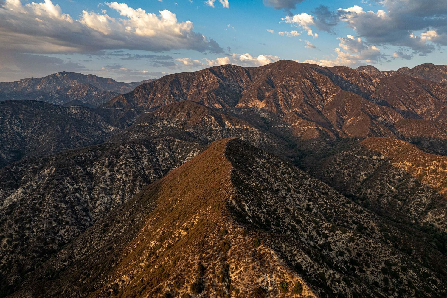 Mountain range landscape at sunset with golden light illuminating rugged peaks.