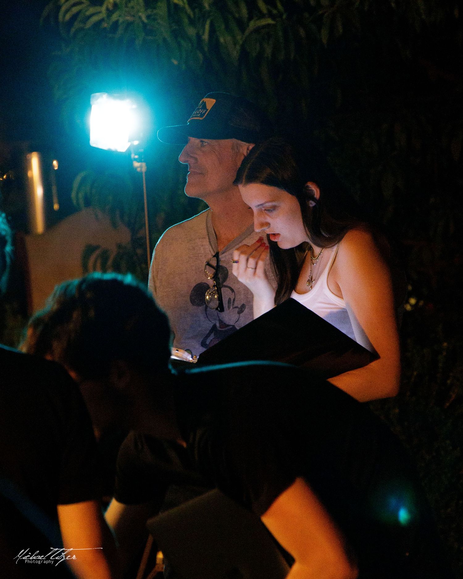 Atmospheric night shoot with silhouettes against teal lighting and camera equipment.