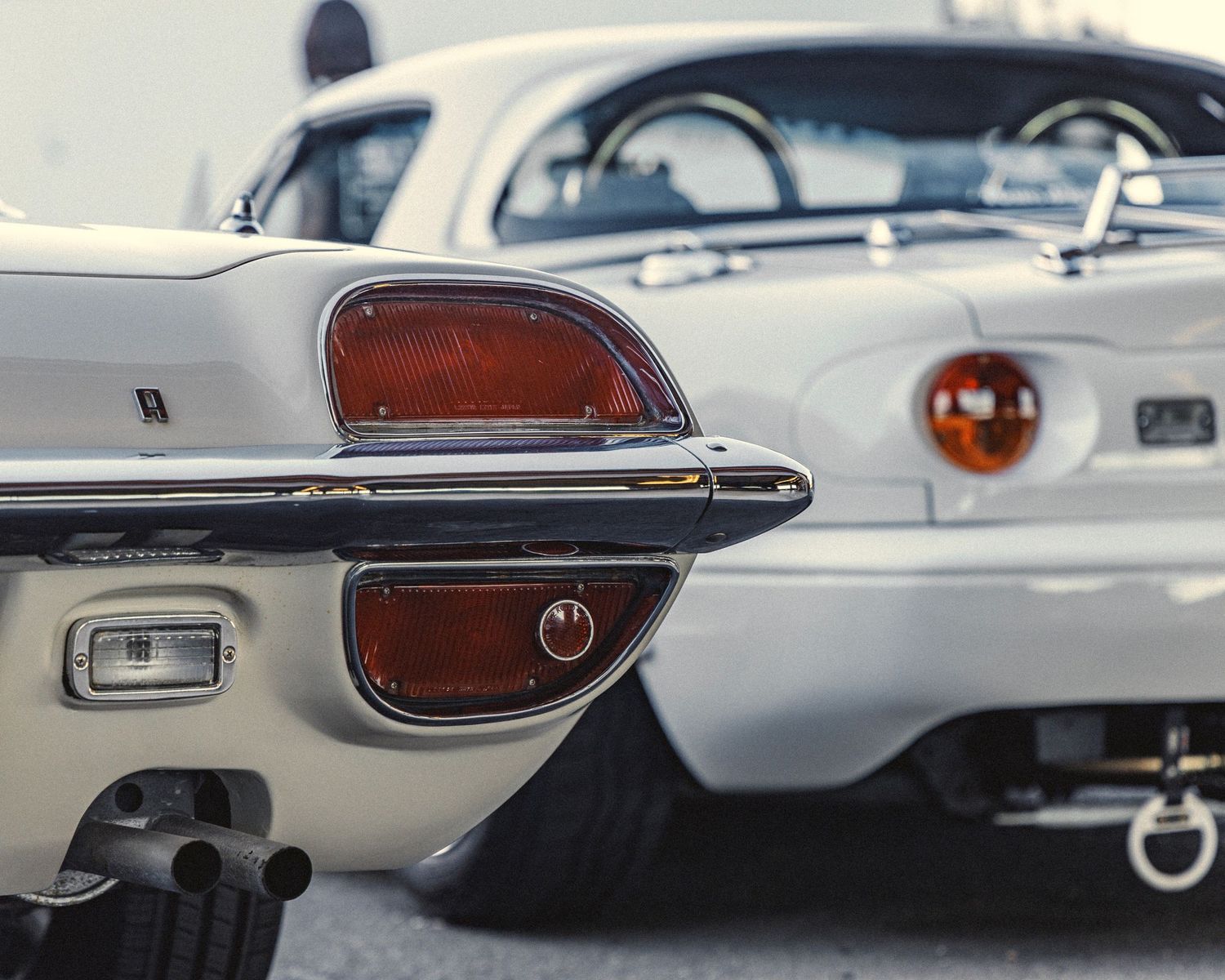 Detail shots of chrome trim and body panels on a vintage white sports car.
