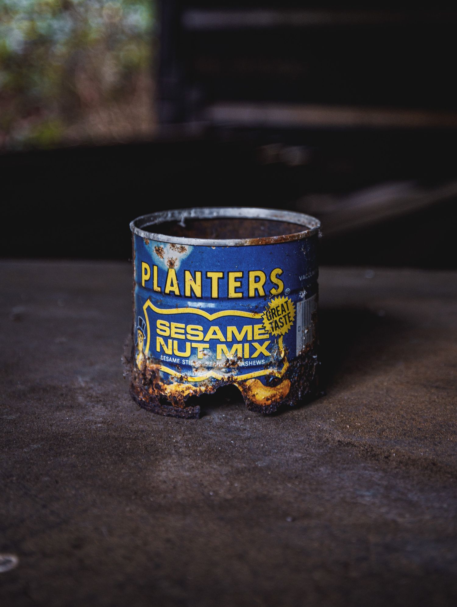 Weathered vintage Planters nut mix and sesame snack tins arranged on a dark surface.