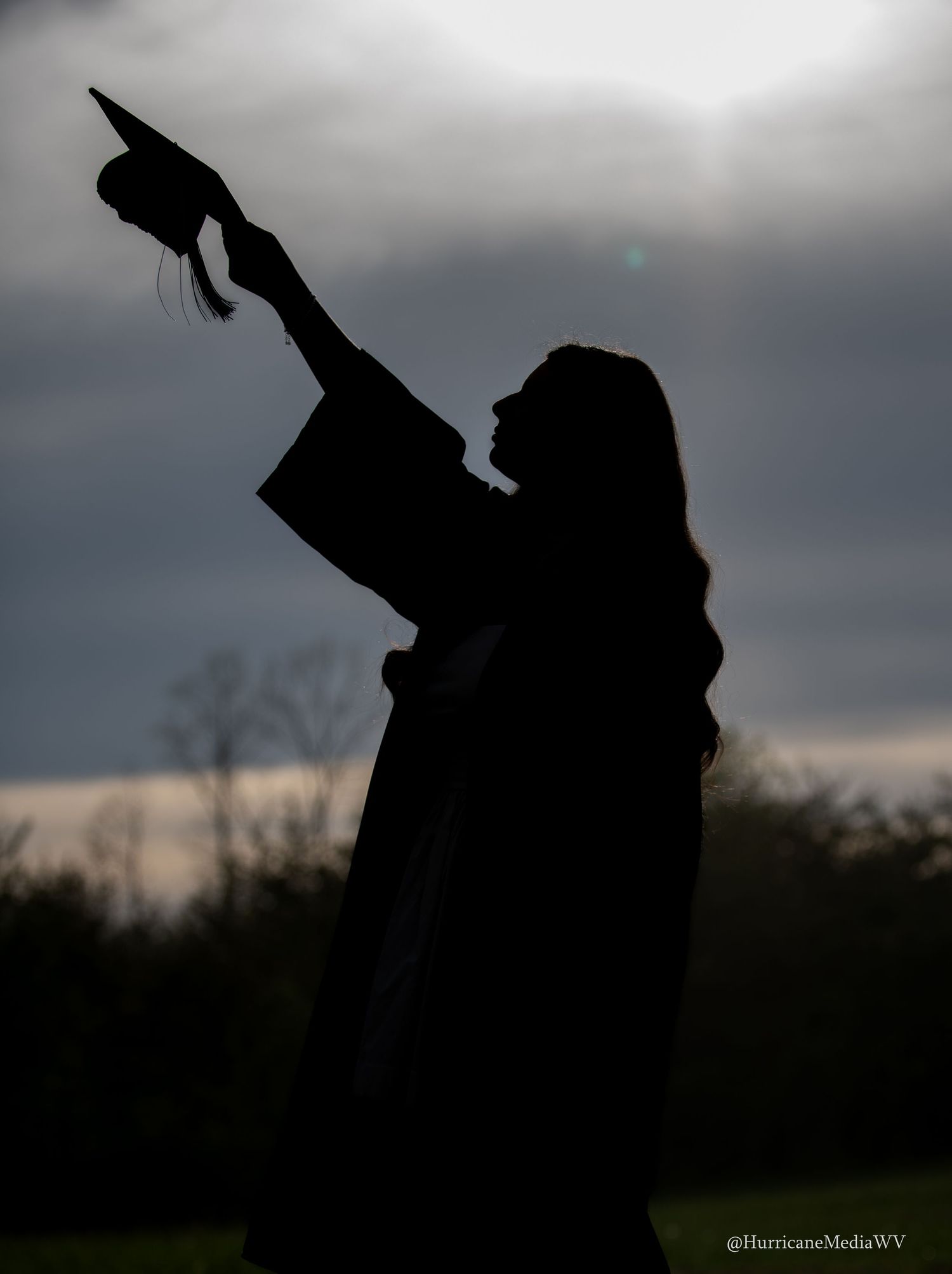 Silhouetted figures pose dramatically against a stormy sky at dusk.