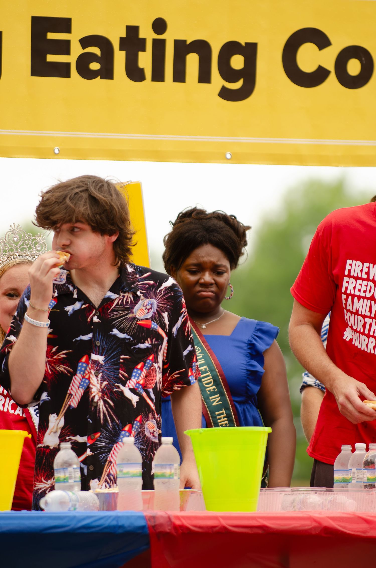 Contestants compete in an outdoor eating competition at a summer event.