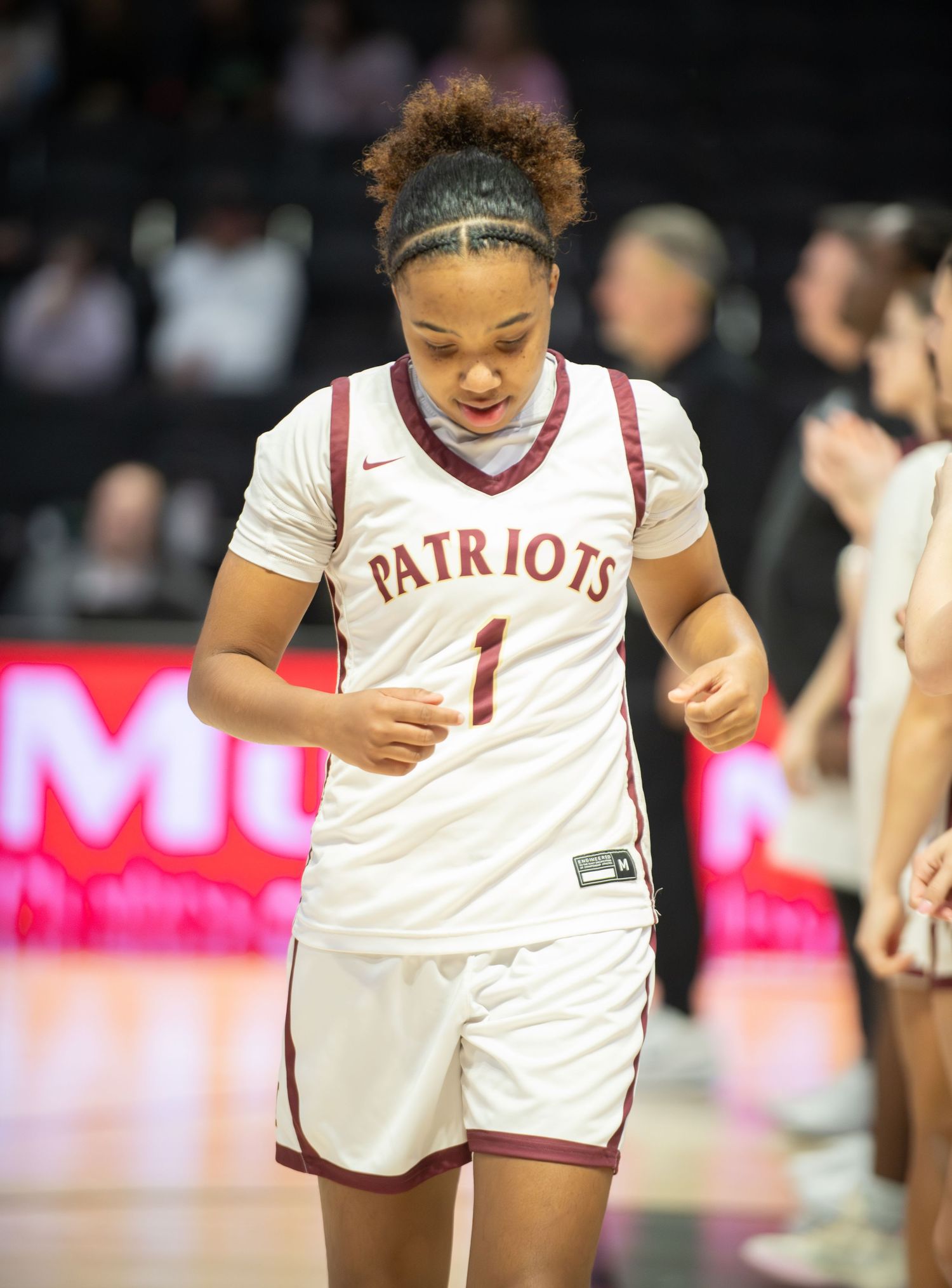 Basketball player in white Patriots uniform celebrates during intense game action.