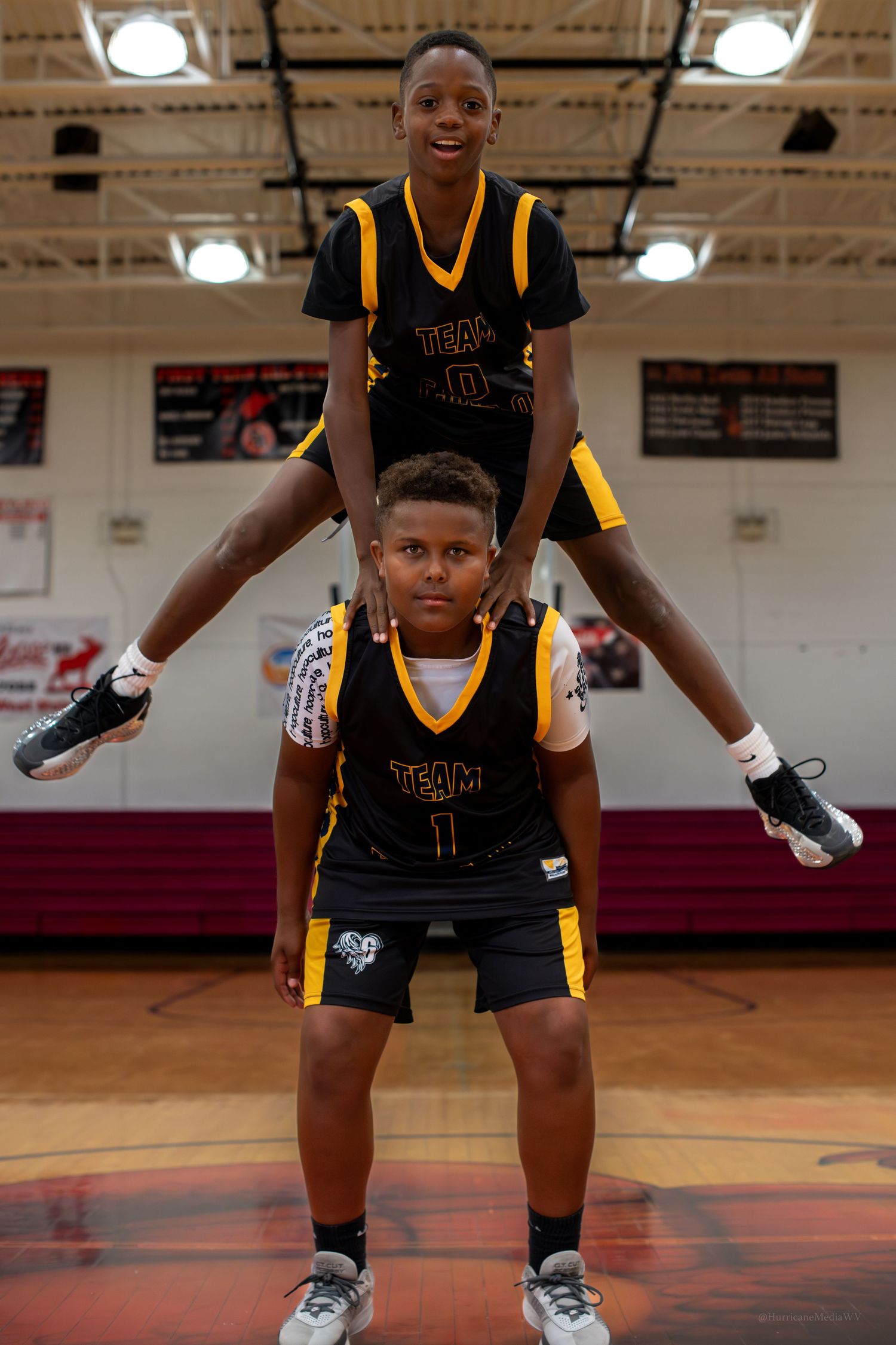 Athletes in black and gold uniforms warming up in a gymnasium.