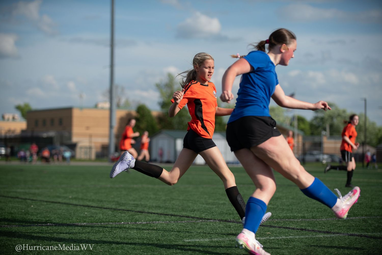 Soccer players in orange and blue jerseys compete for ball during match on grass field.