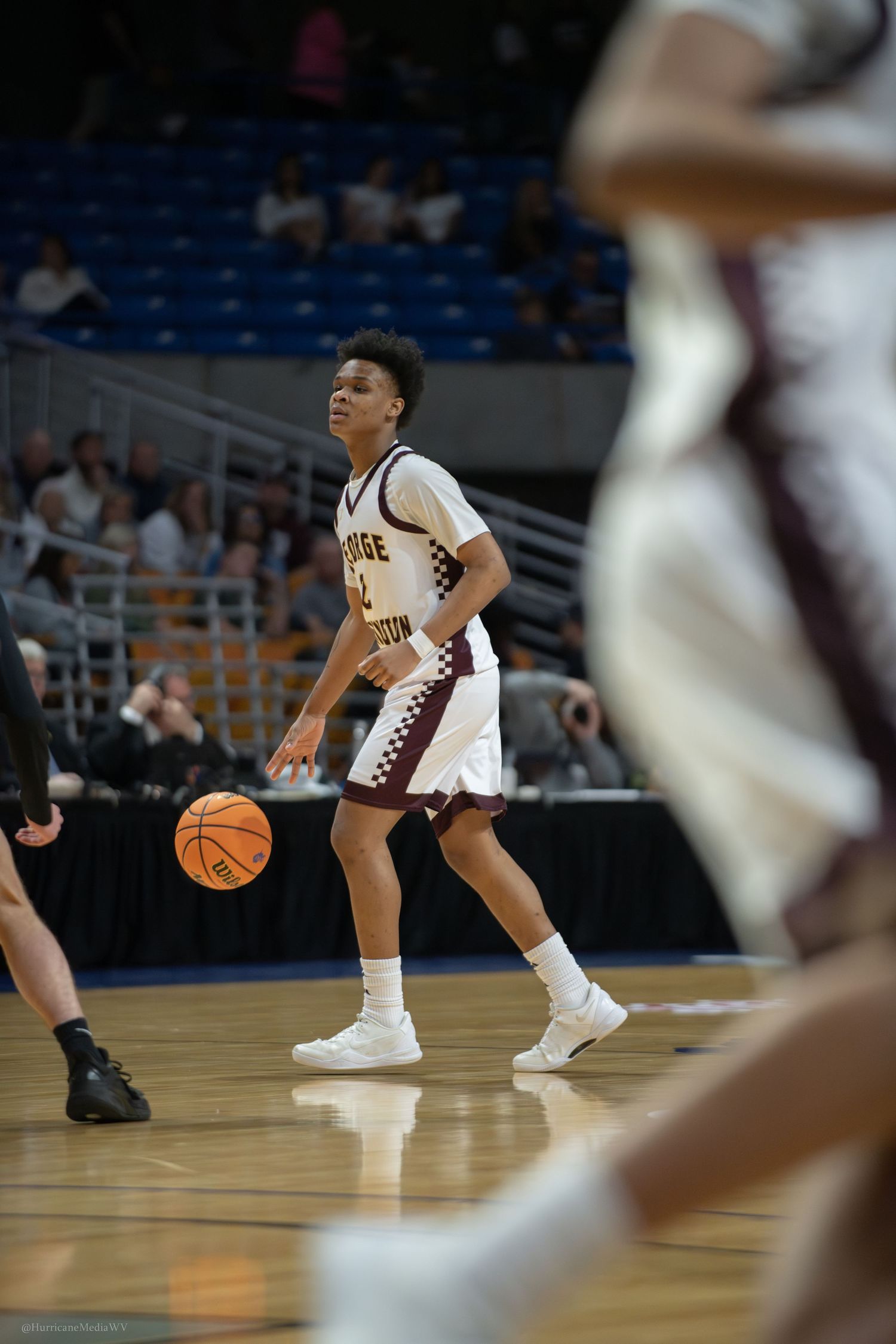 Basketball player dribbles on court during competitive game action.