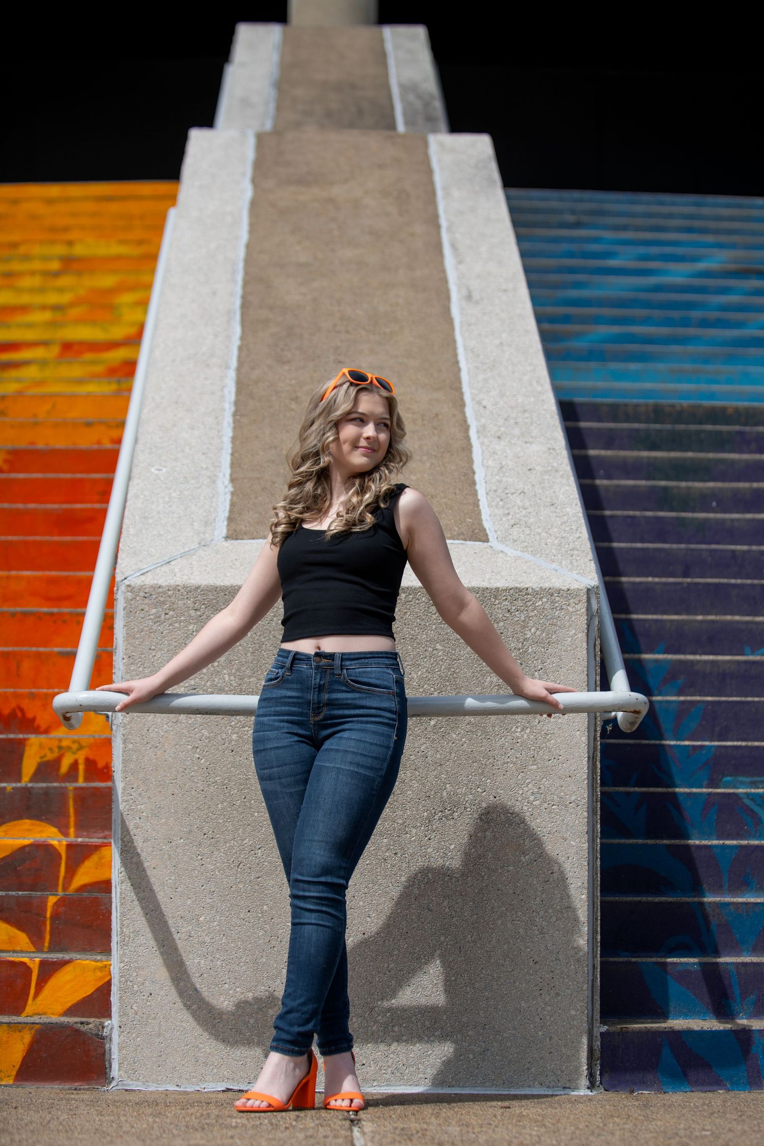 A casual portrait on colorful painted stairs with urban art in the background.