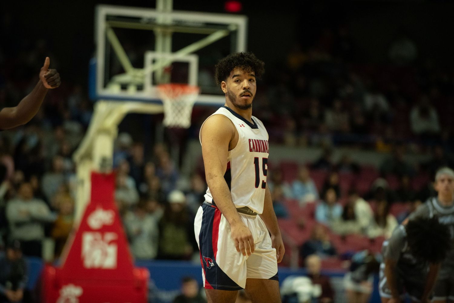Basketball player in white uniform gestures during game in arena.