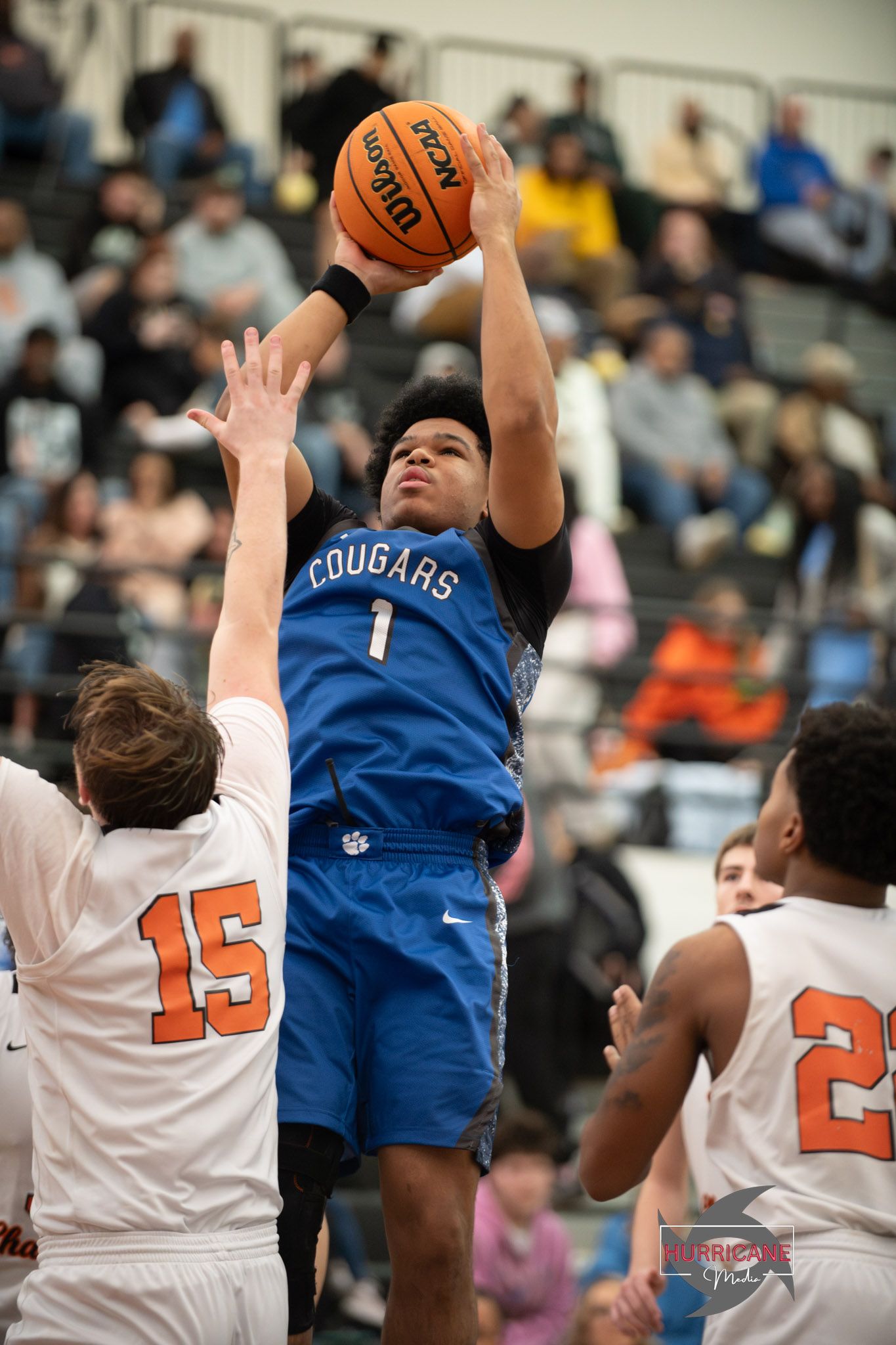 Basketball players in blue and white jerseys leap for a rebound during an intense game sequence.