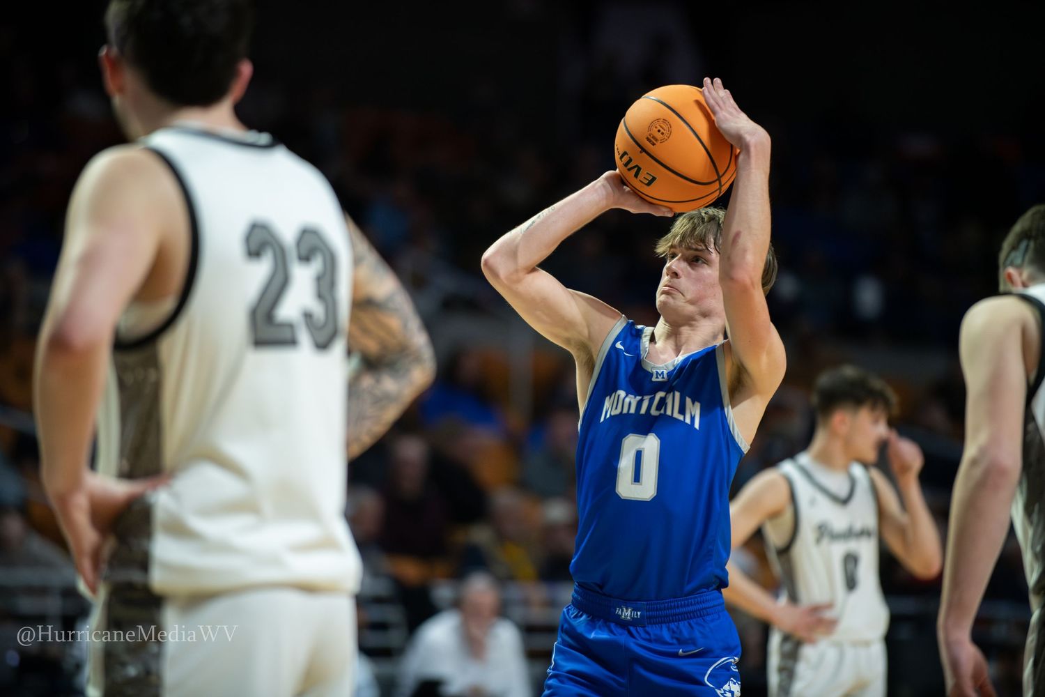 Basketball players compete during an intense game with players in blue and white uniforms on the court.