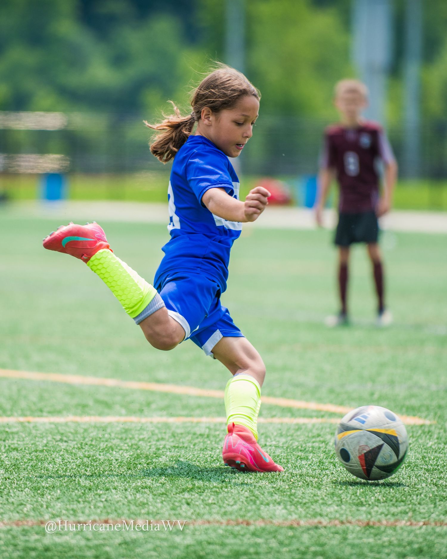 Close up of soccer player's feet kicking ball on grass field.