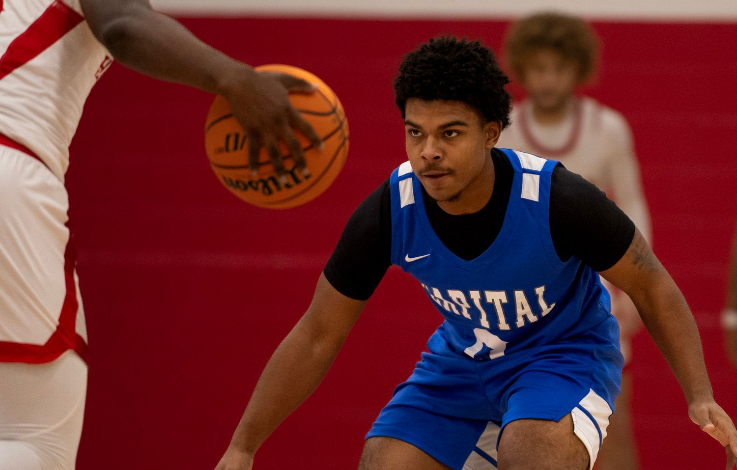 Basketball player in blue jersey plays defense during intense game action.