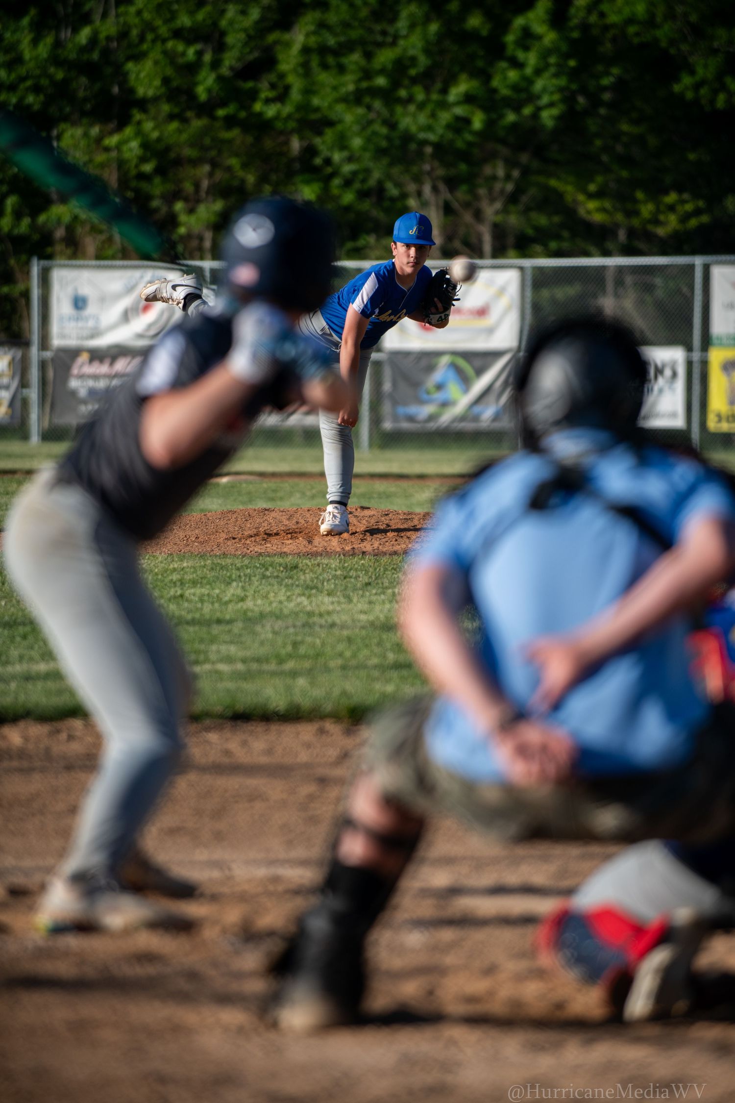 Baseball players in action during game with pitcher and catcher in focus.