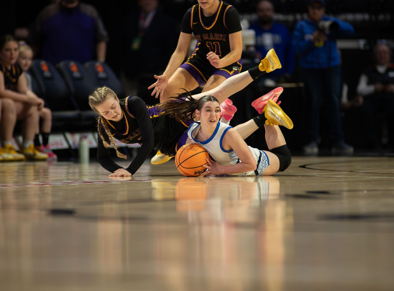 Basketball players scramble for a loose ball during an intense game on the hardwood court.