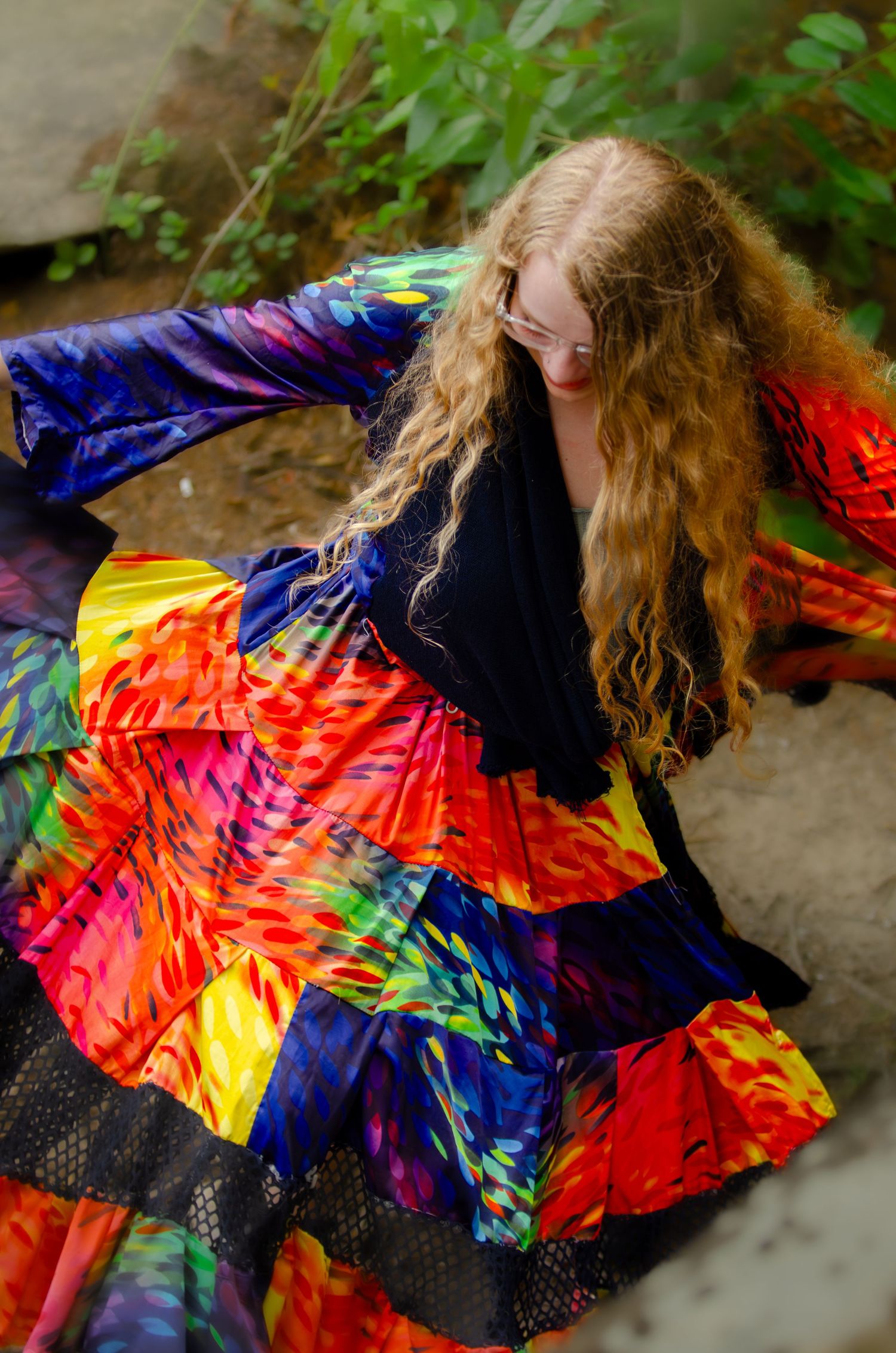 A spinning dancer in a vibrant tie-dye dress with flowing multicolored patterns.