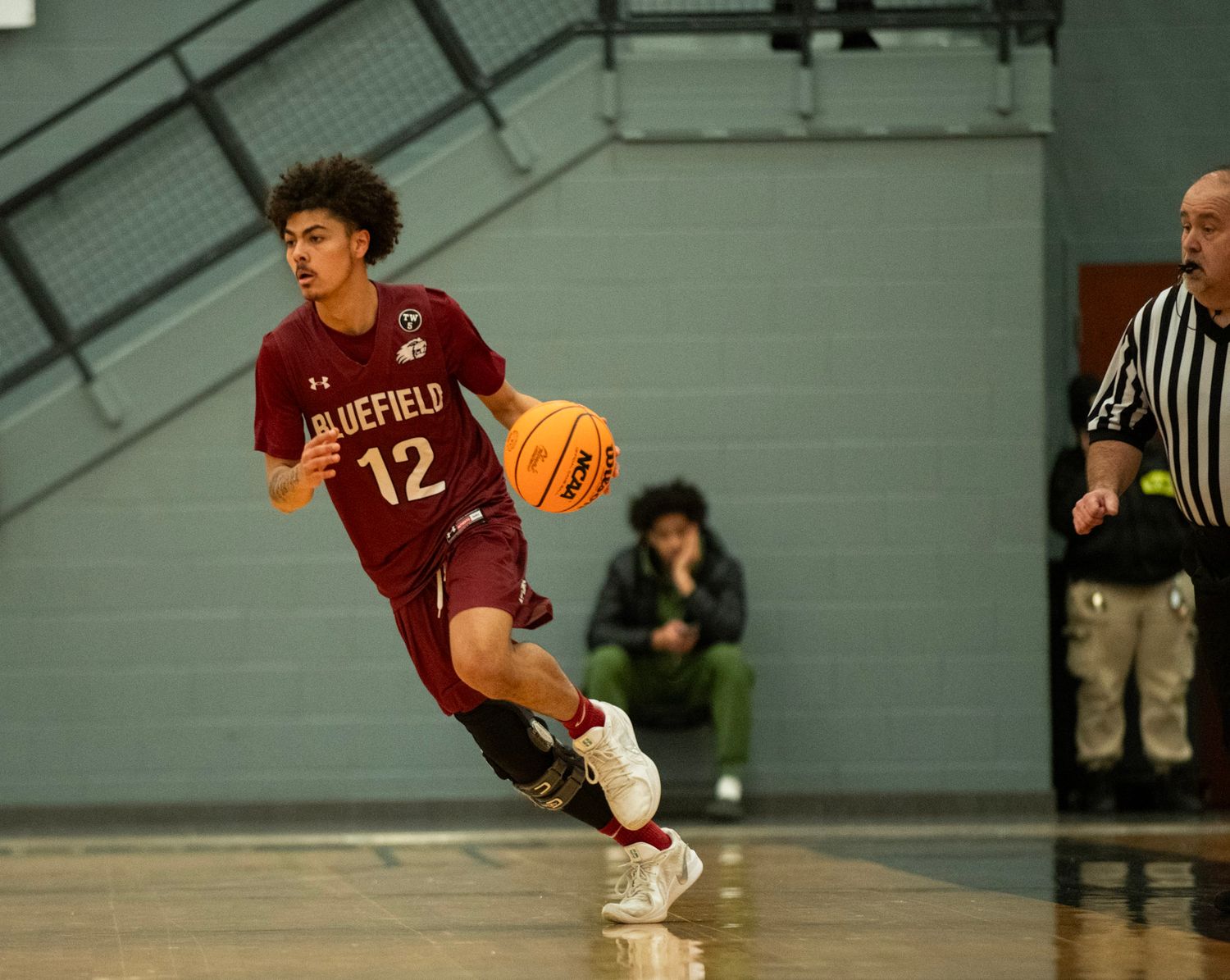 Basketball player in maroon uniform dribbles down the court during a game.