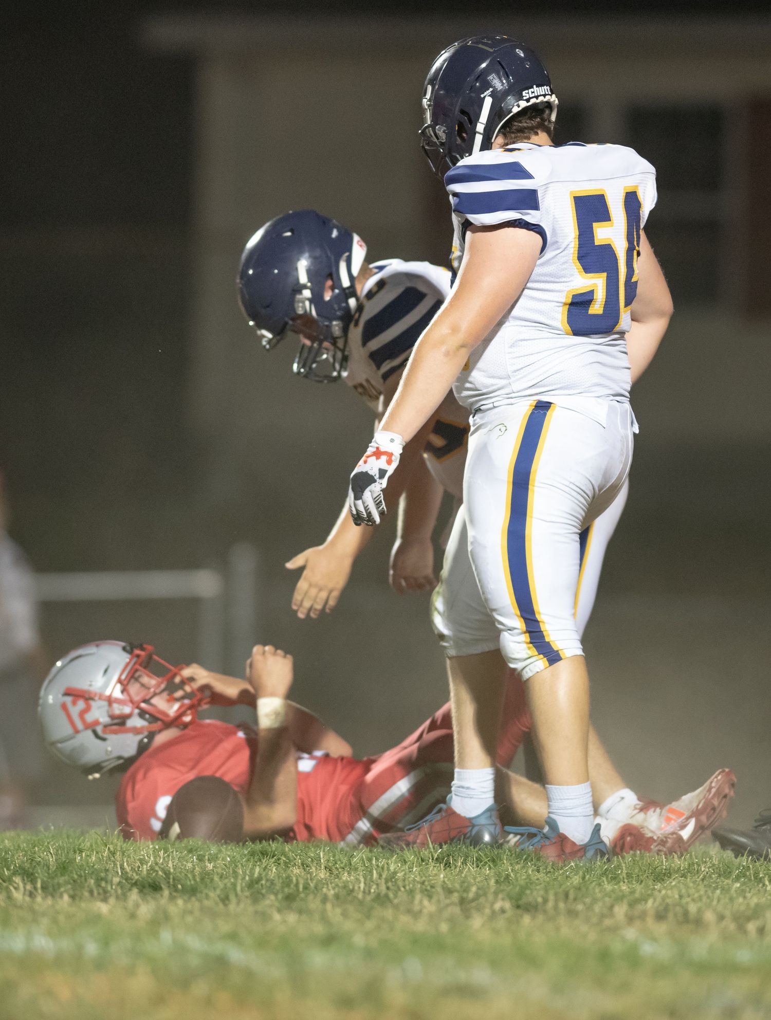 Football players from opposing teams interact during a tackle play on the field.