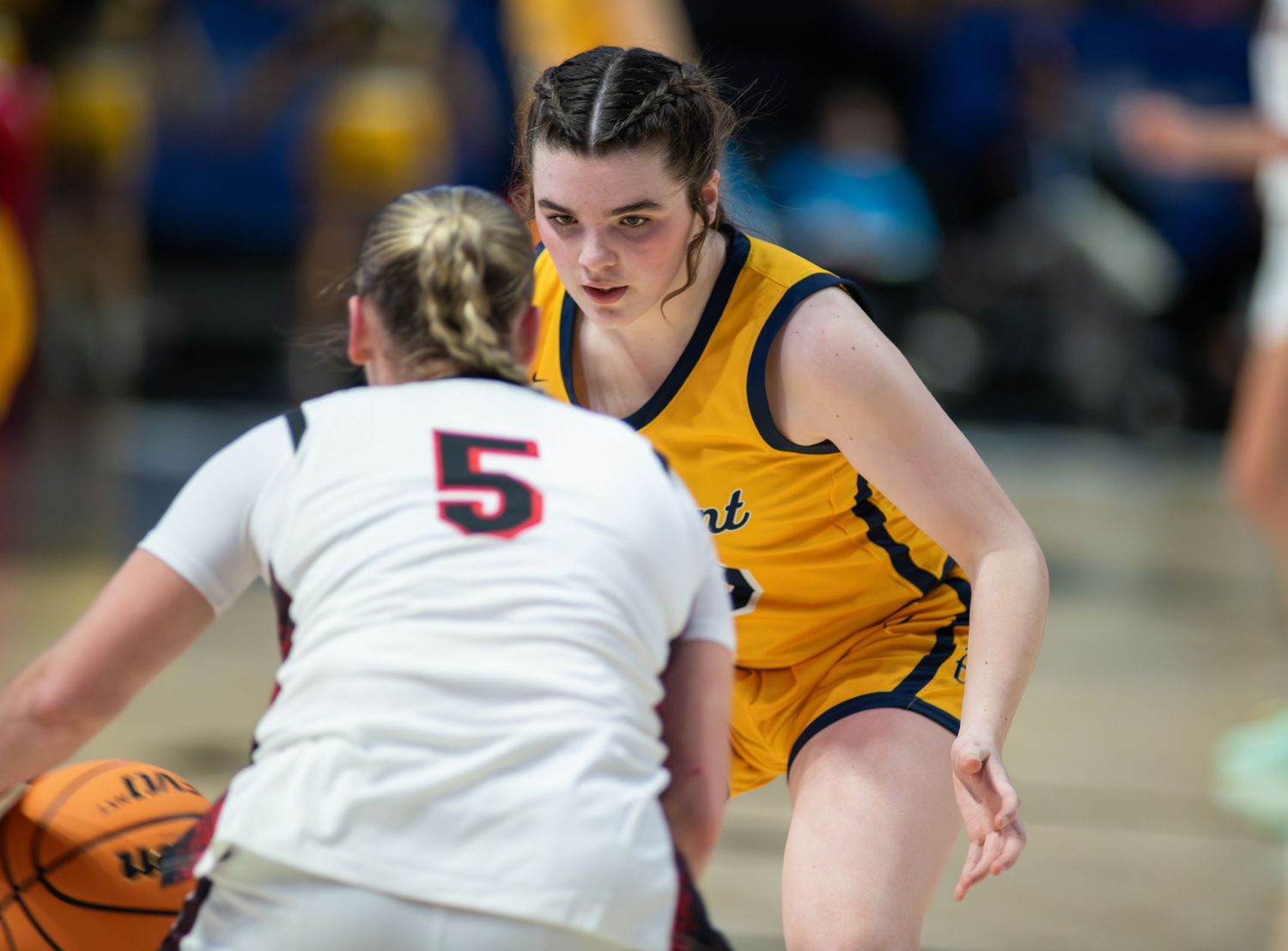 Basketball players in yellow and white uniforms compete for possession during an intense game.