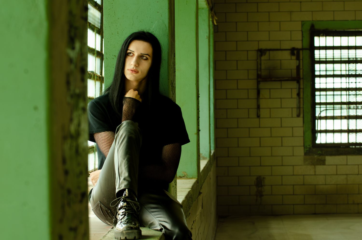 Atmospheric green-tinted portrait taken in industrial brick building with window light.