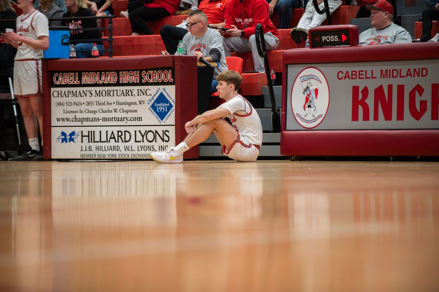 A basketball court floor with red banners and advertising signage visible along the sidelines.