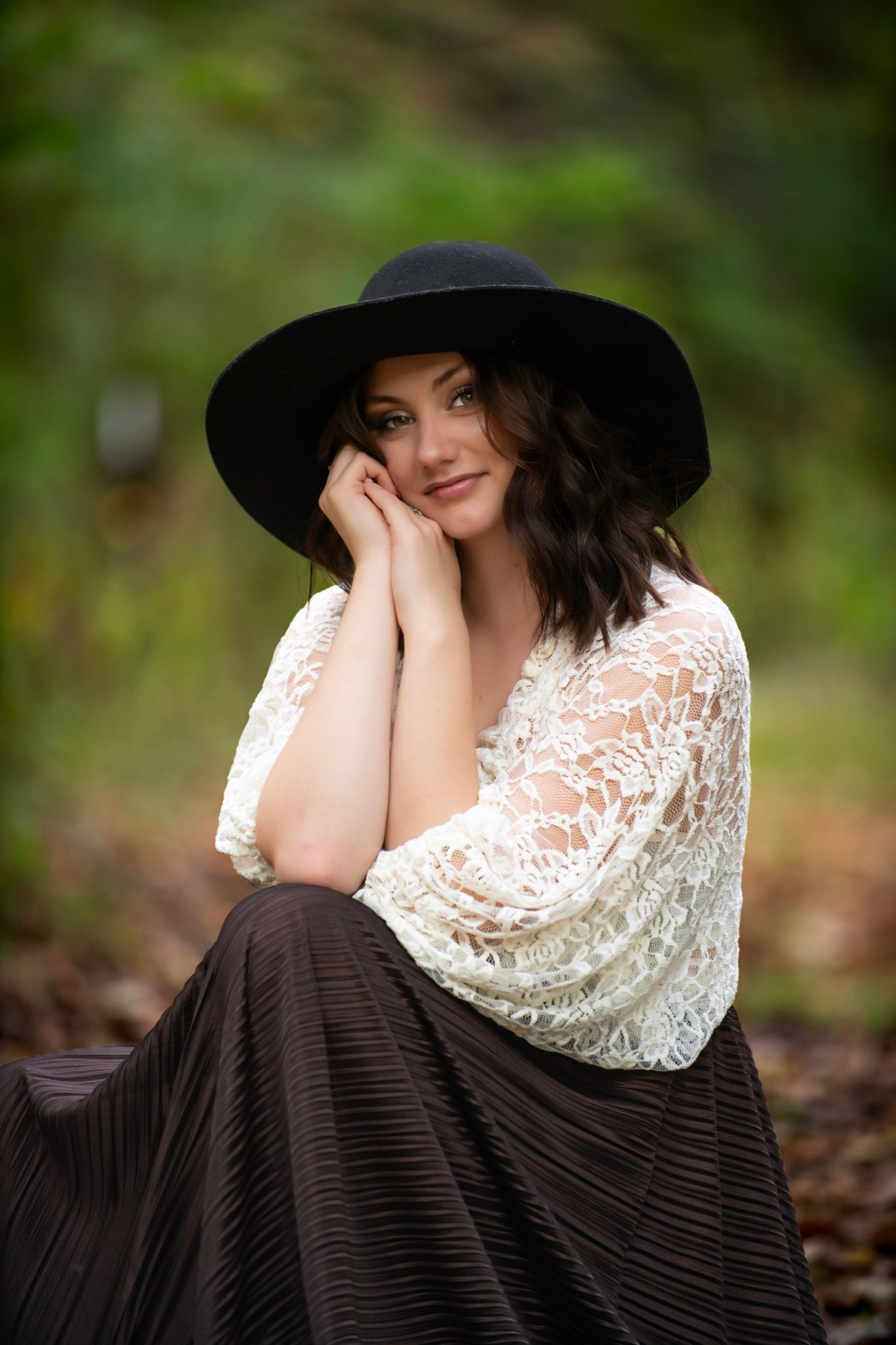 Portrait of person wearing black hat and lace top in outdoor autumn setting.