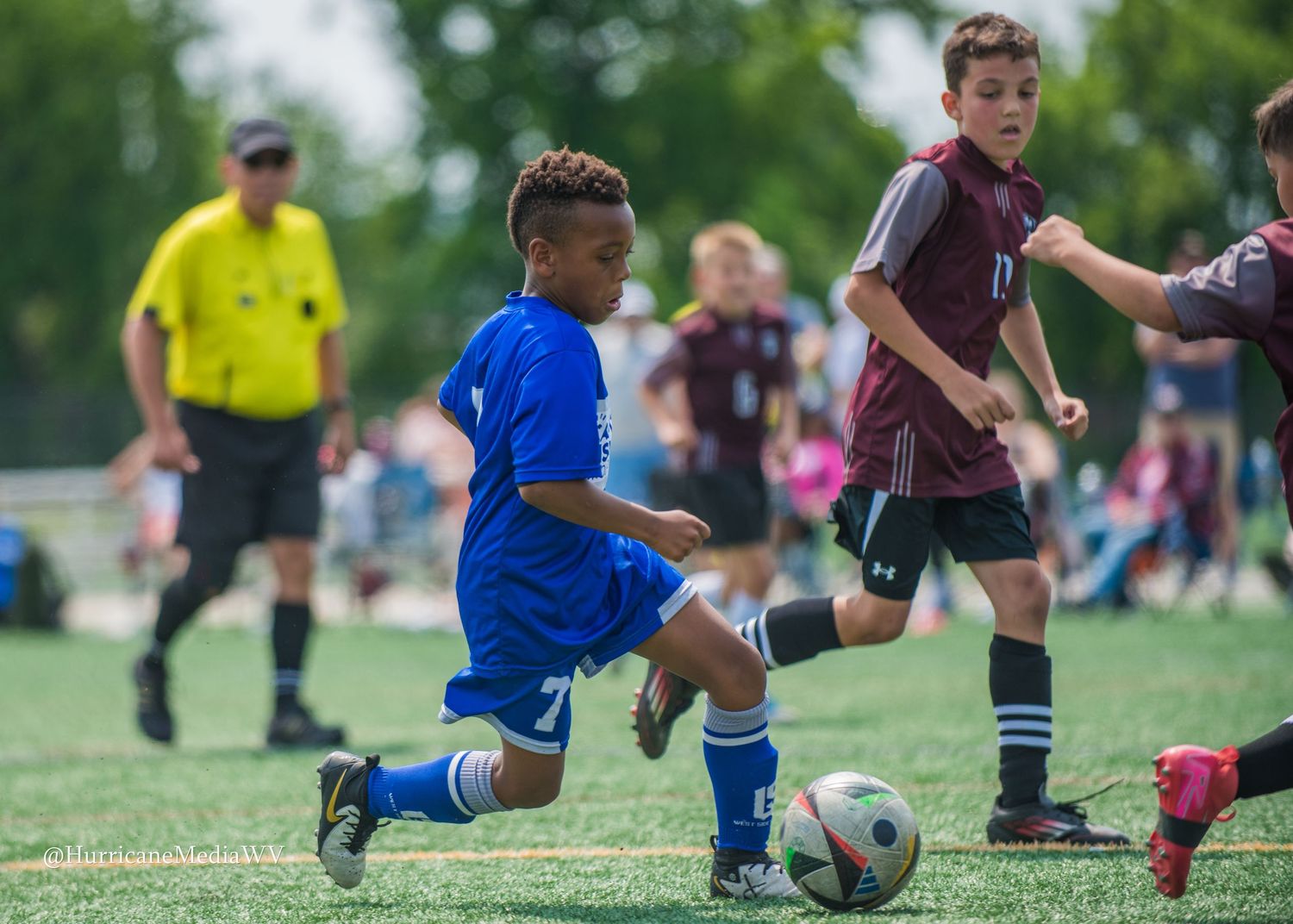 Youth soccer players compete for the ball during a match on a grass field.