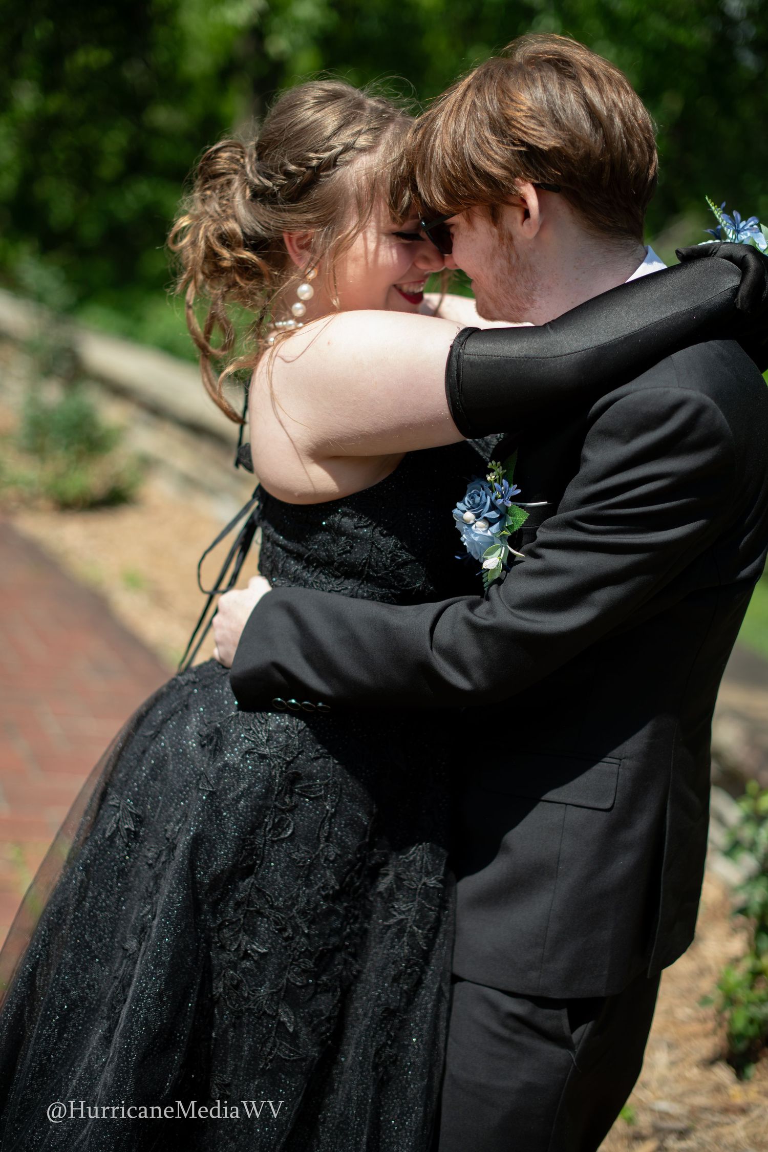 Couple sharing intimate moment in formal wear at outdoor garden setting.