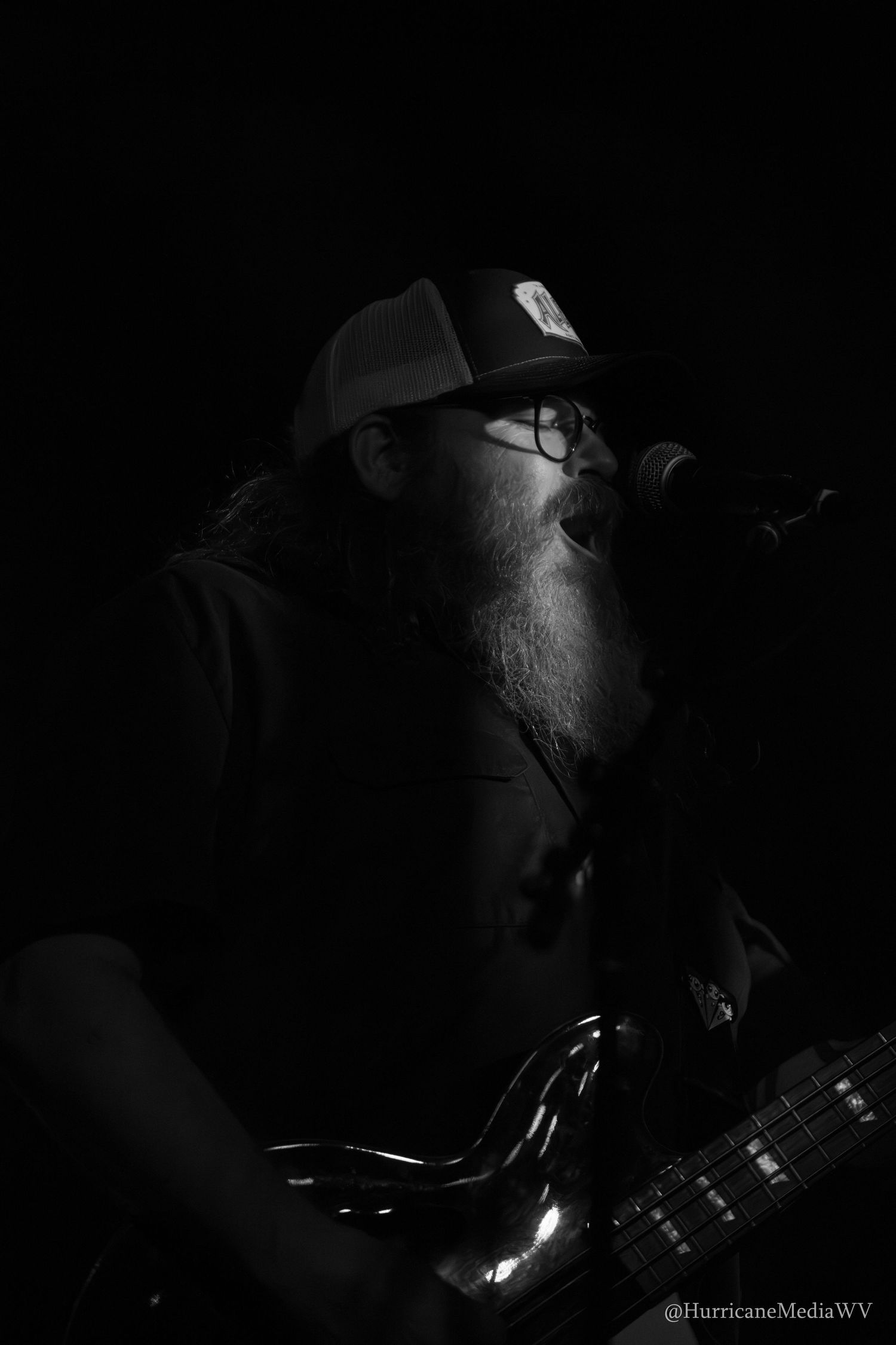 Dramatic black and white close-up images show a musician with guitar performing in moody low-key lighting.