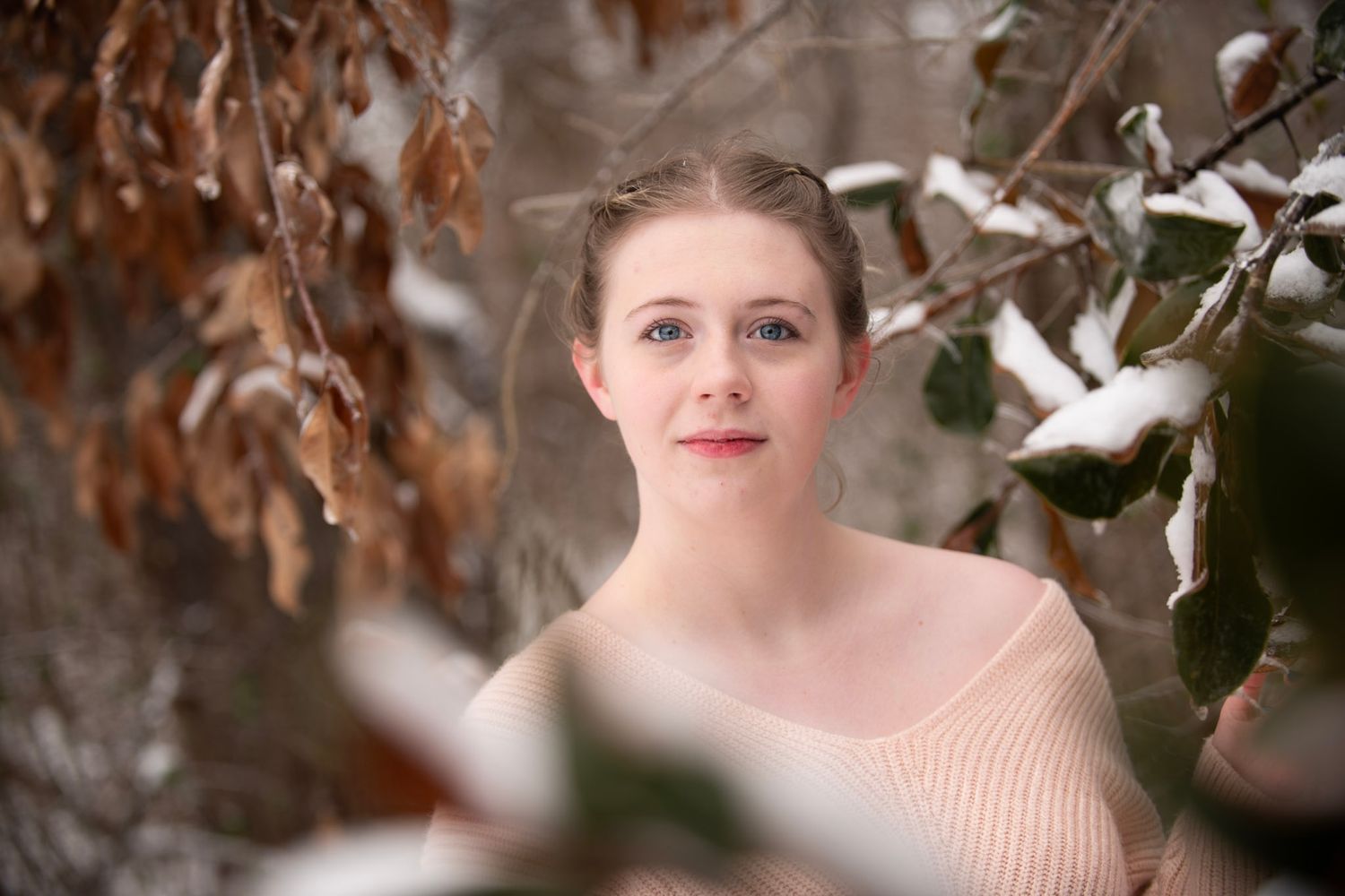 Portrait in soft winter lighting with snowy branches framing the composition.