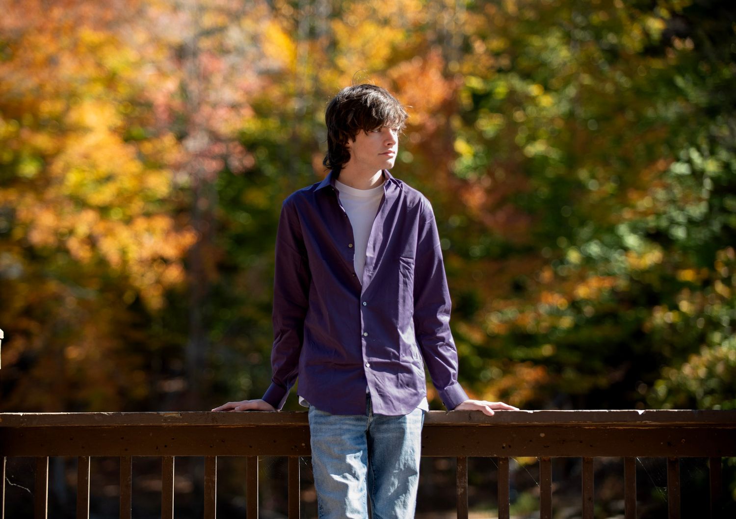 Fall season portrait on wooden deck with autumn foliage in background.