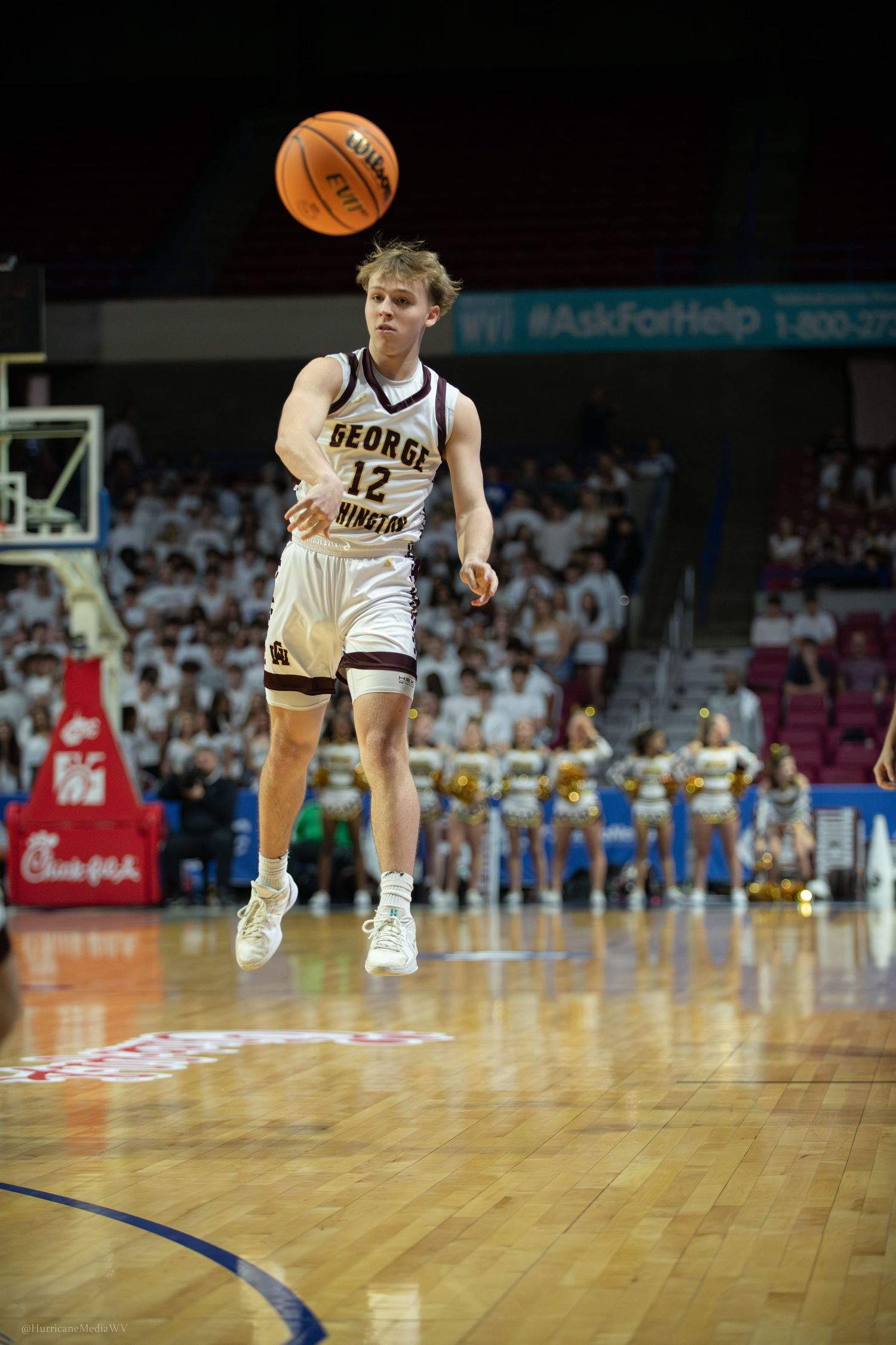 Basketball player in white George Smith uniform leaps with ball during game.