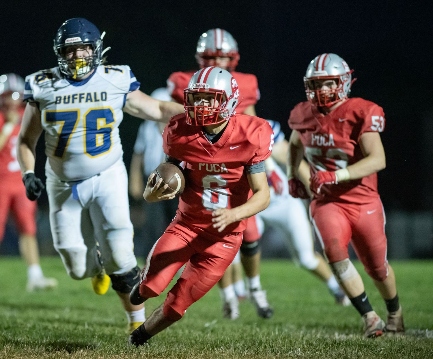 High school football players in red and blue uniforms competing during an intense game.