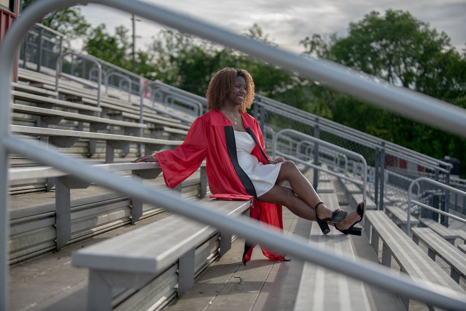 A candid moment captured on bleacher seats featuring red graduation attire.