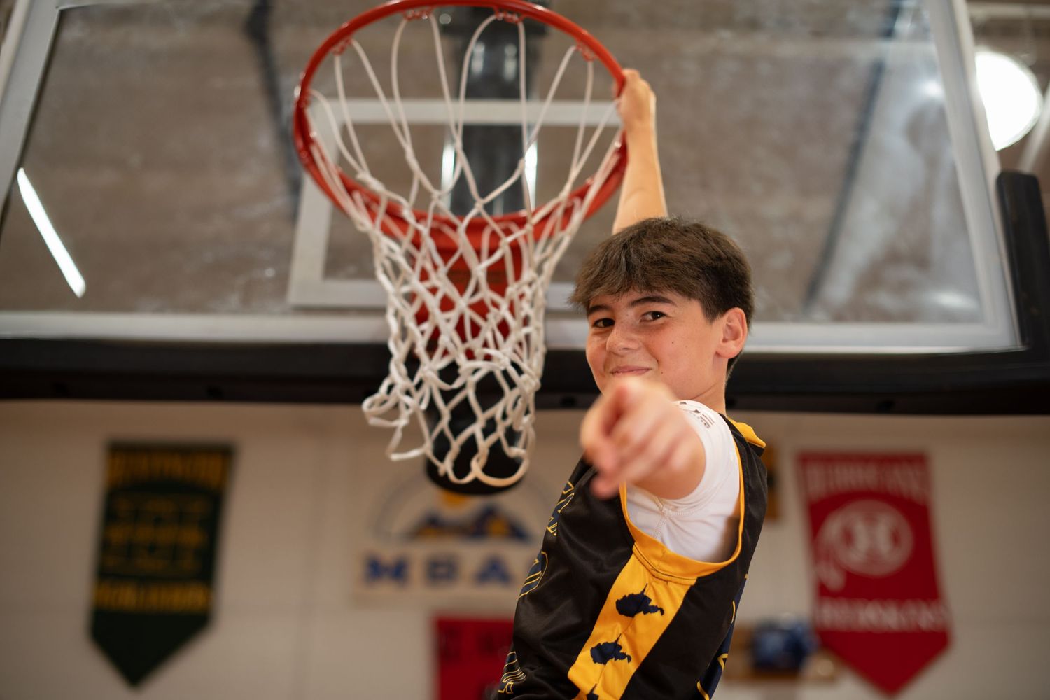 Basketball player reaching up toward hoop during practice session in gym.