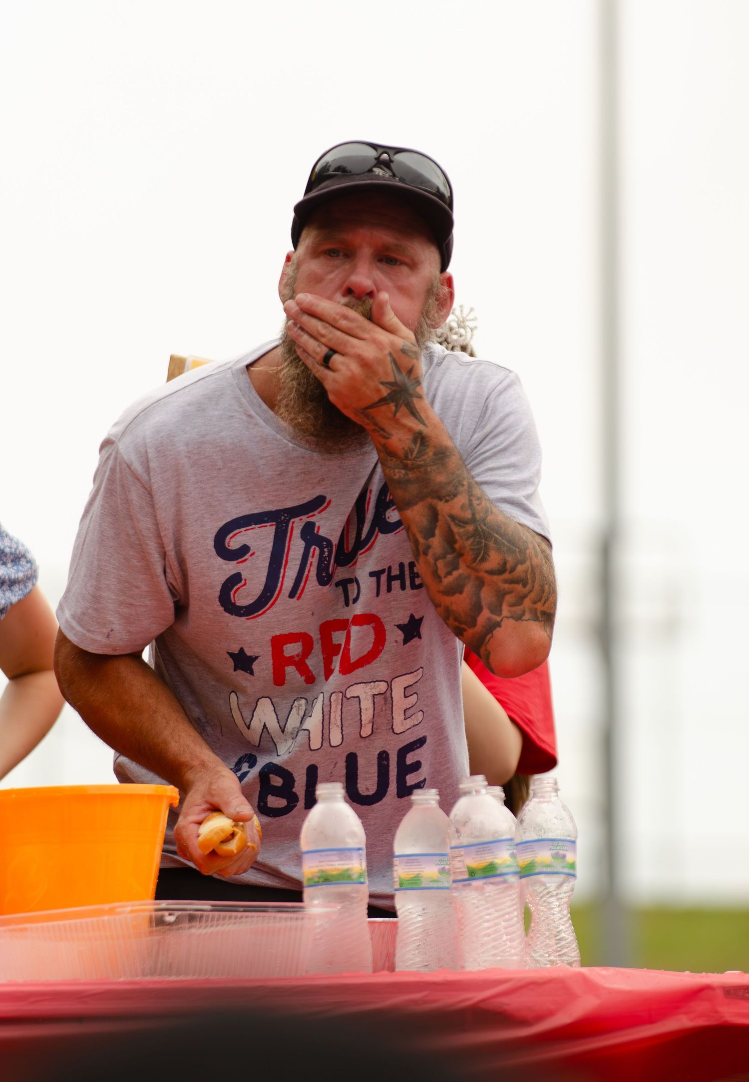 Participant reacts during an eating contest wearing a patriotic themed t-shirt.