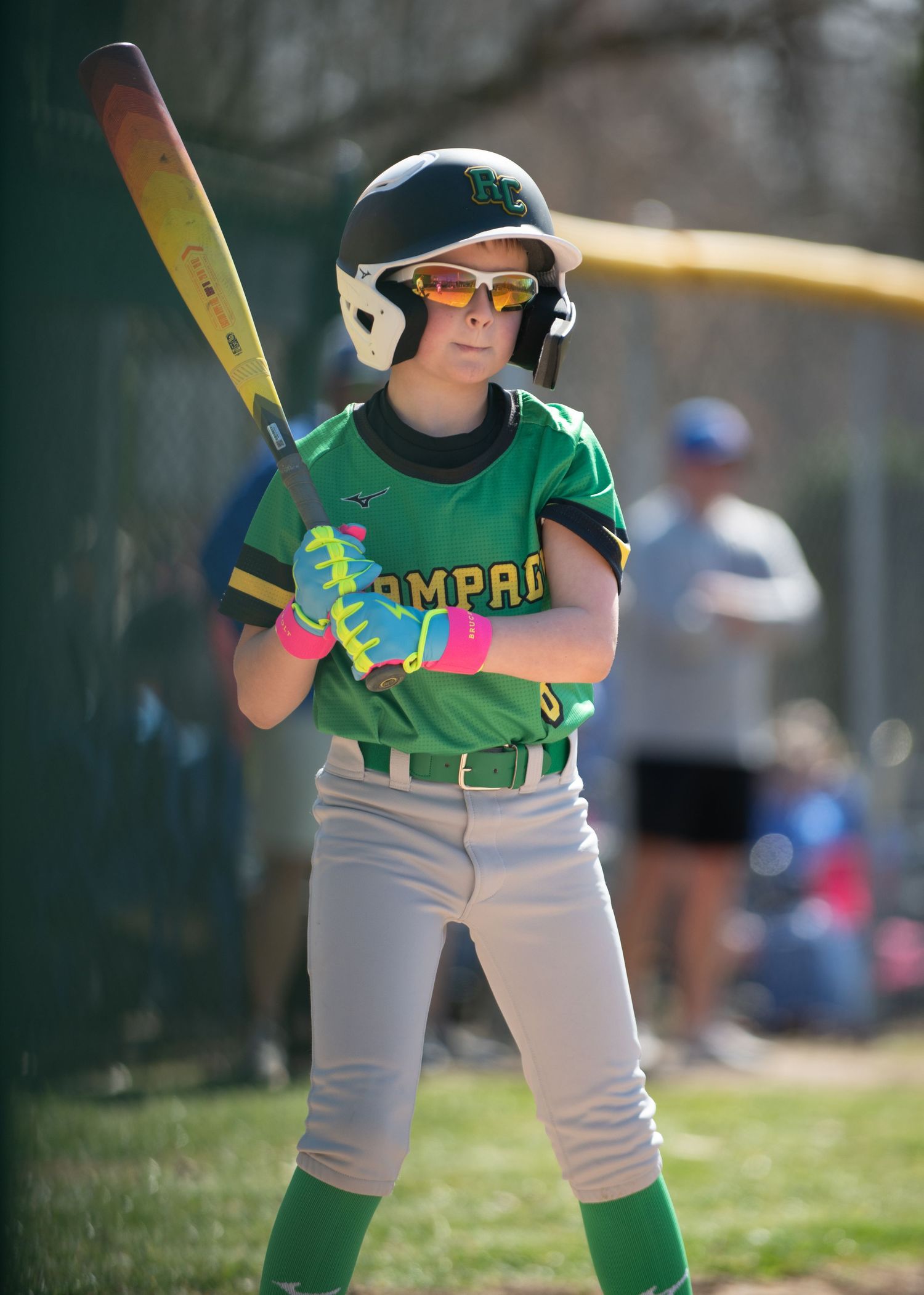 Youth baseball player in green uniform at bat during game.