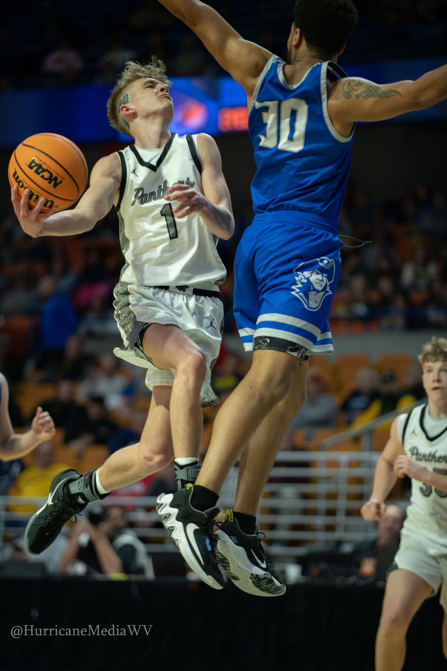 Basketball player in white jersey drives to the basket against defender in blue during intense game action.