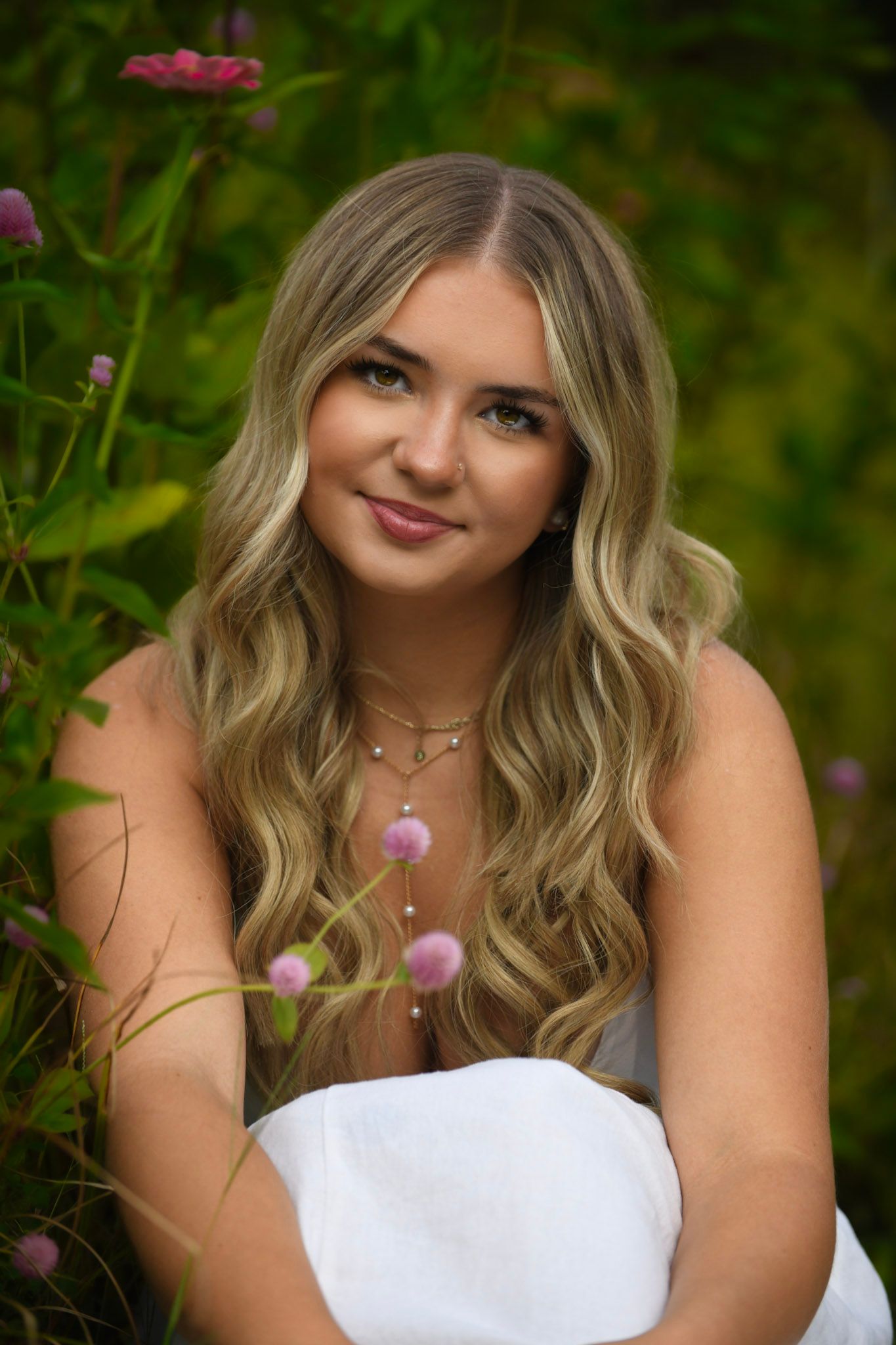 Senior portrait in a white dress among purple wildflowers with natural outdoor lighting.