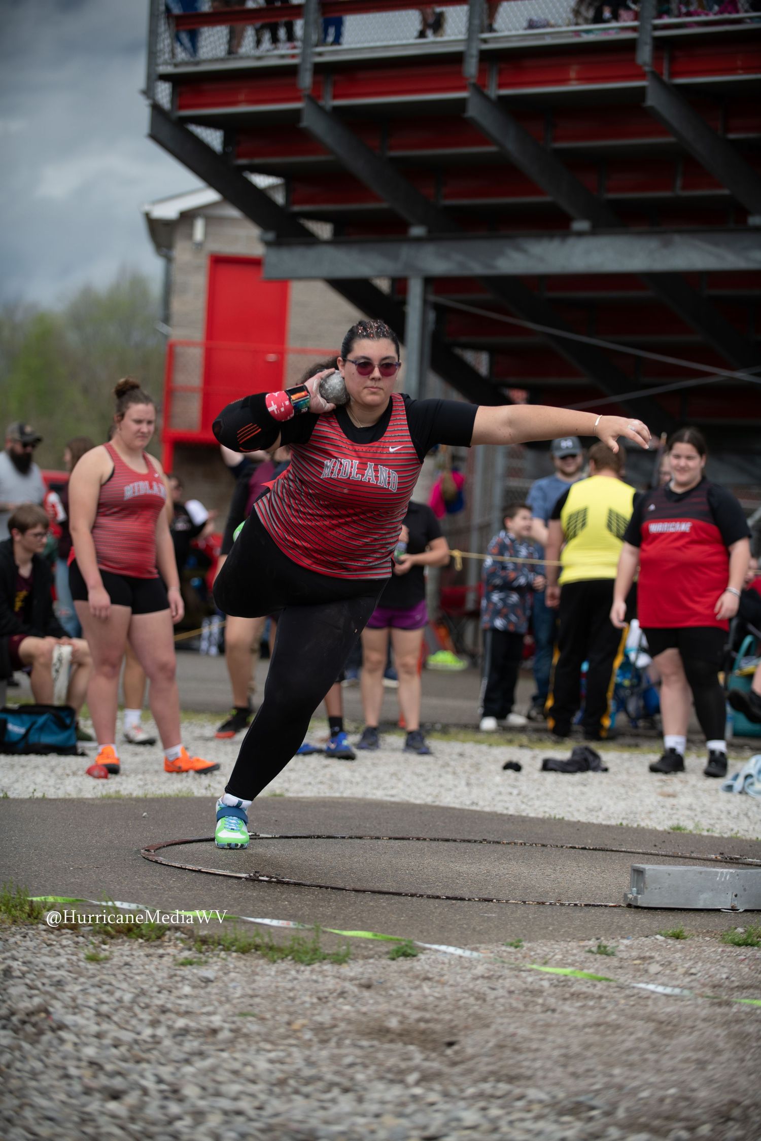 Red and black clad athletes perform dynamic lunges during an outdoor fitness competition.