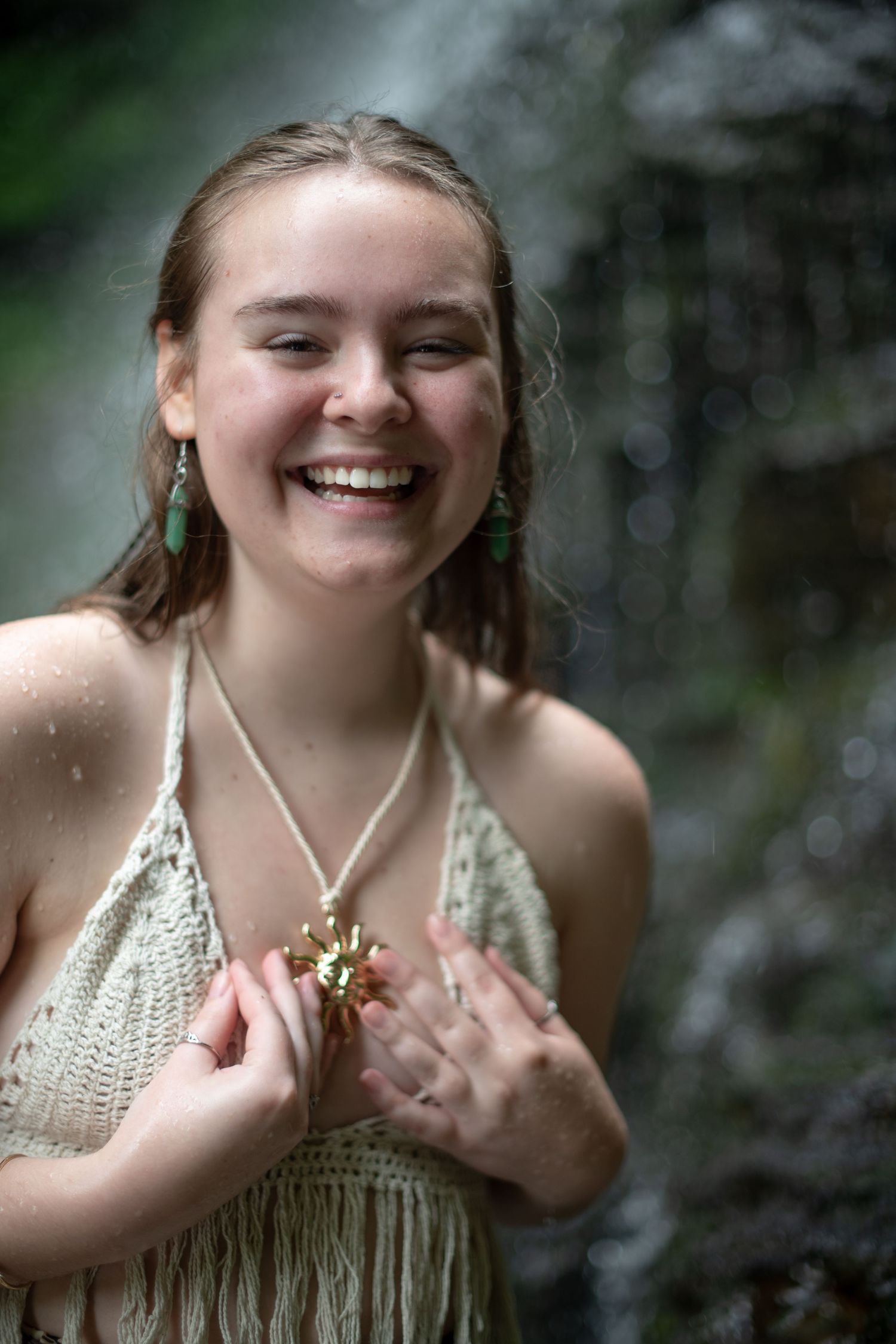 A joyful moment outdoors wearing turquoise earrings and a cream-colored fringed top against a blurred natural background.