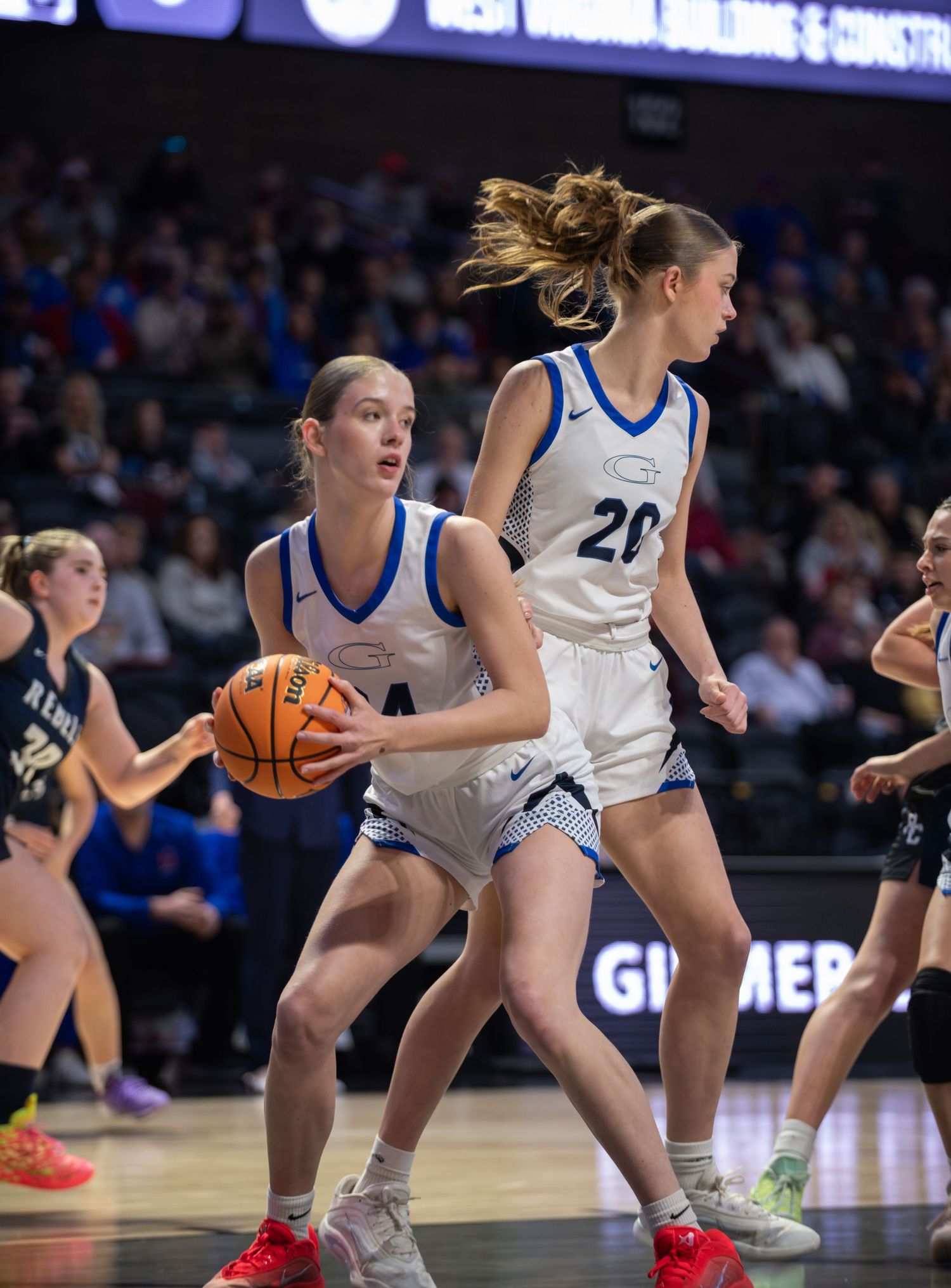 Basketball players dive and stretch across the court floor to gain possession of a loose ball during an intense game.