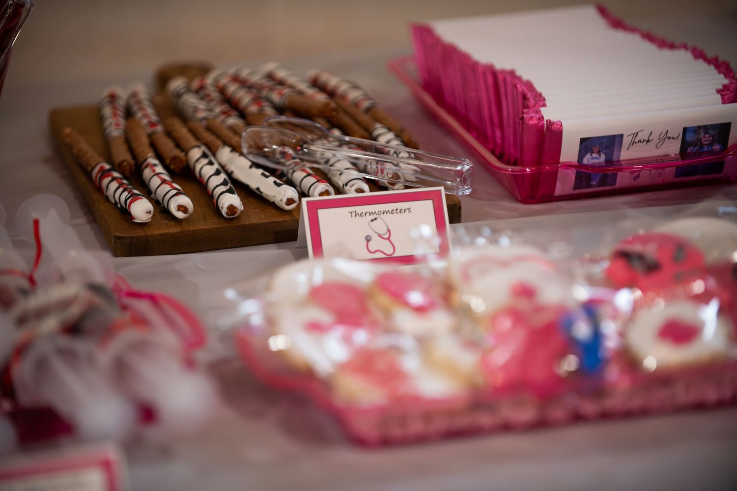 Close-up view of decorated cookies and pink party favors on a table.