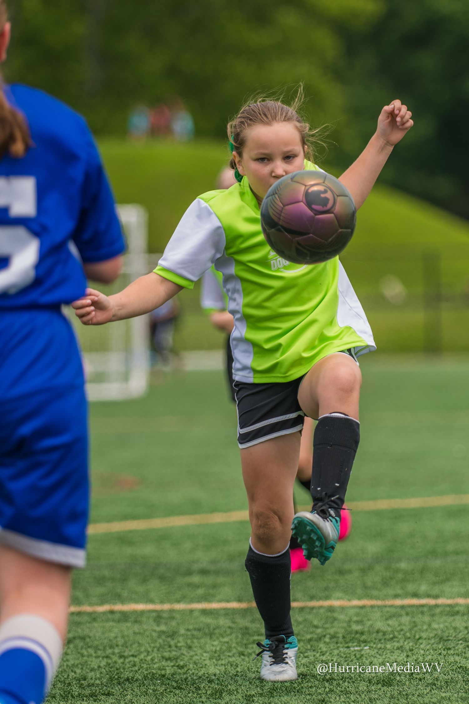 Close up of soccer player's legs kicking ball on artificial turf field.