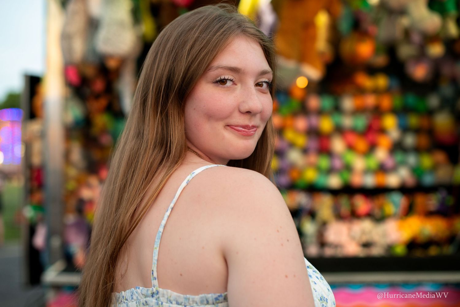 Portrait of someone at a colorful carnival fair with bright lights in the background.