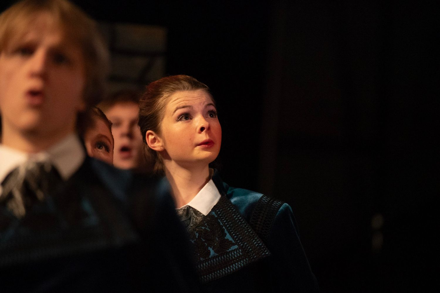 Students in a darkened theater performing in a dramatic stage production.