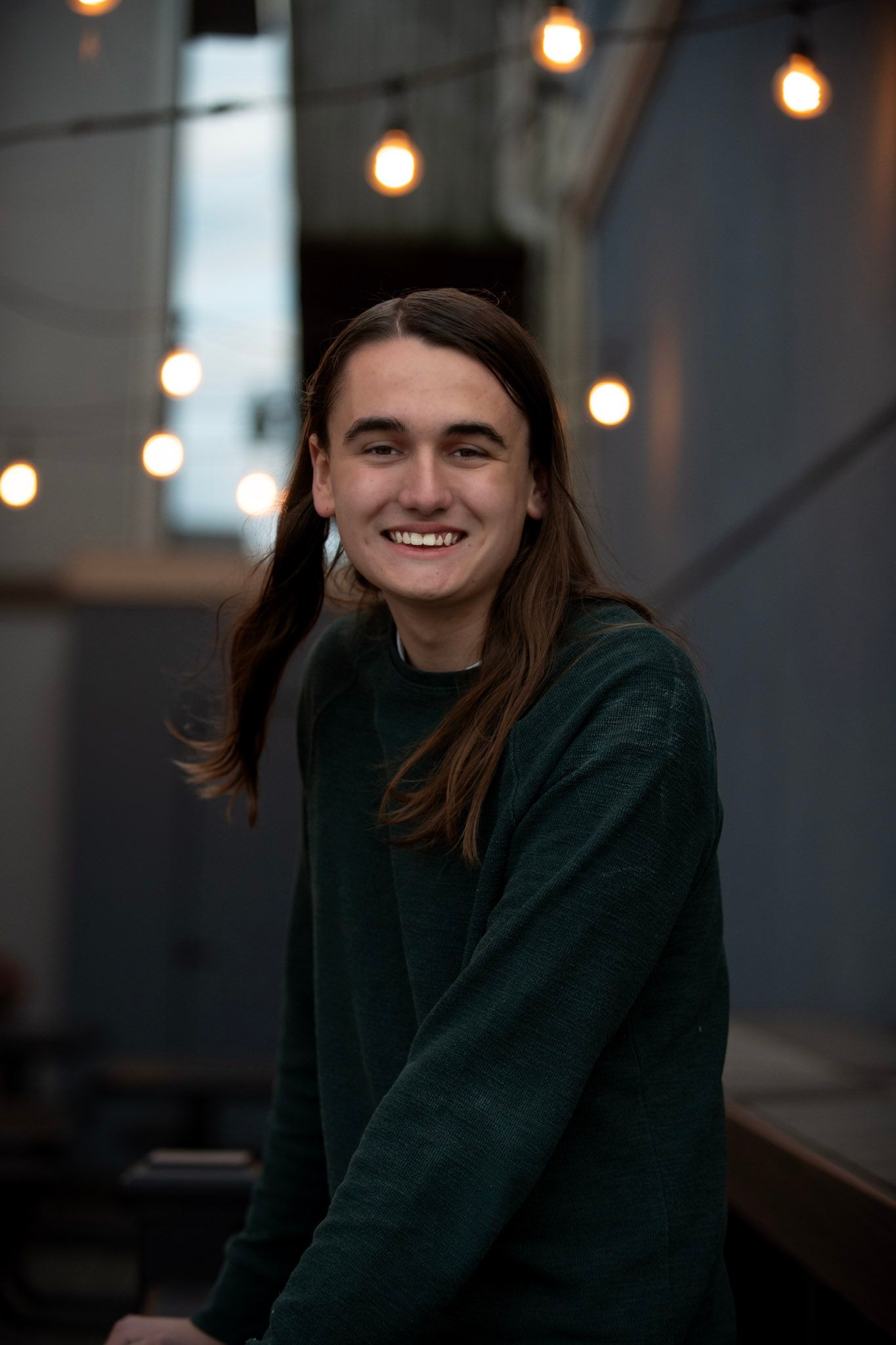 Evening portrait with string lights creating warm bokeh effect in background.
