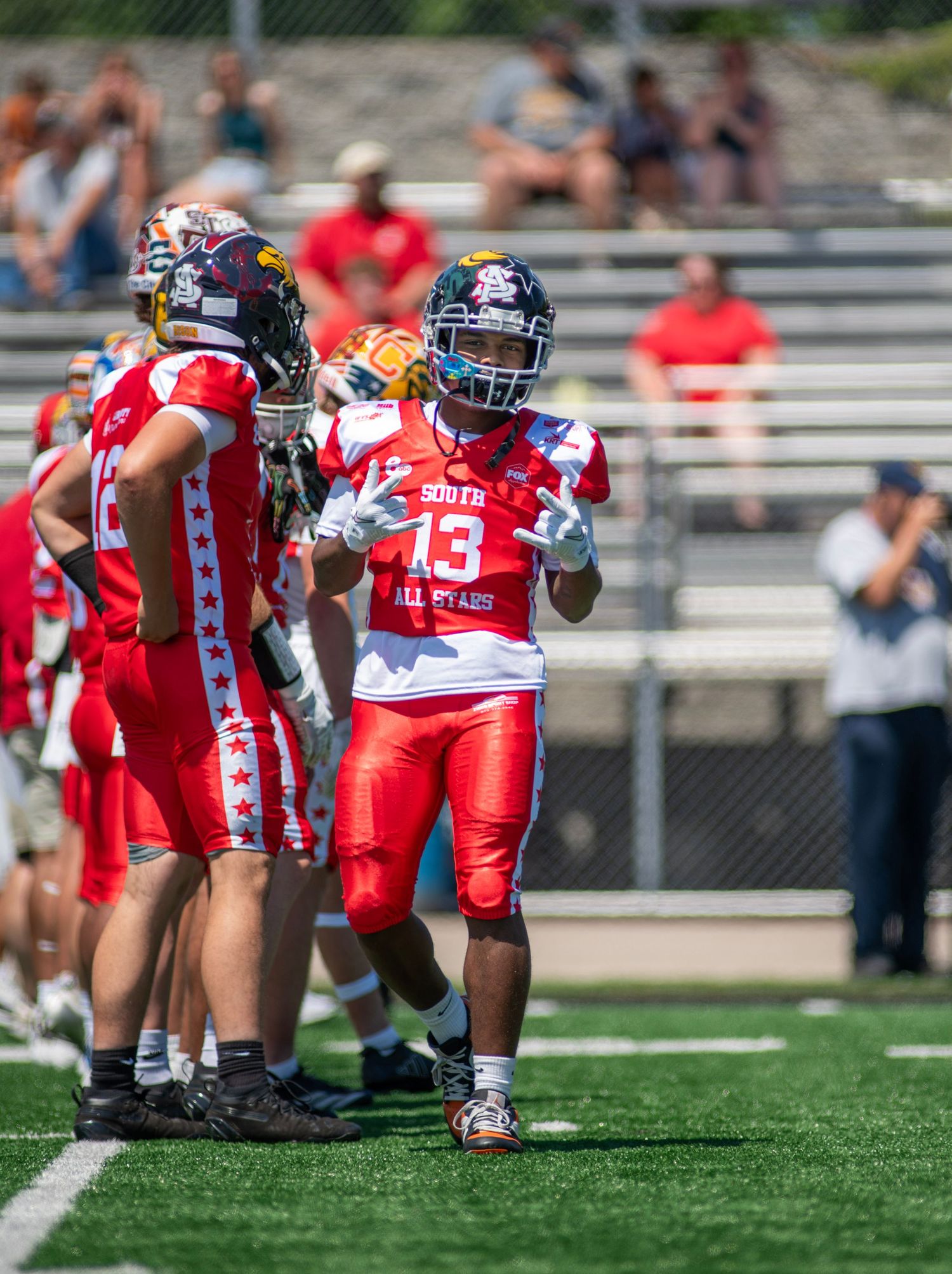 South All-Stars football player #13 in red uniform stands ready on field during youth all-star game.
