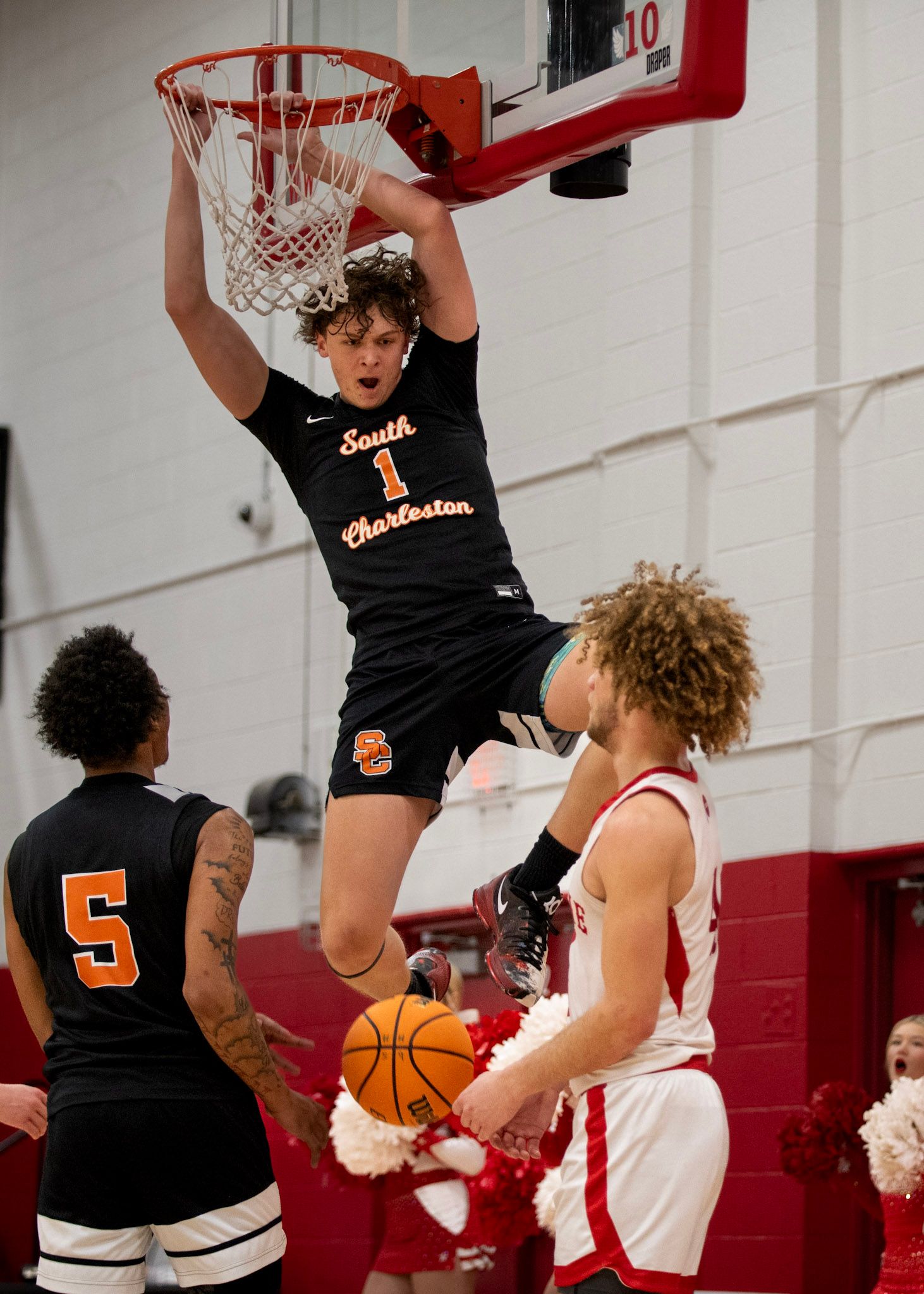 Basketball players from opposing teams battle for position under the hoop during a game.